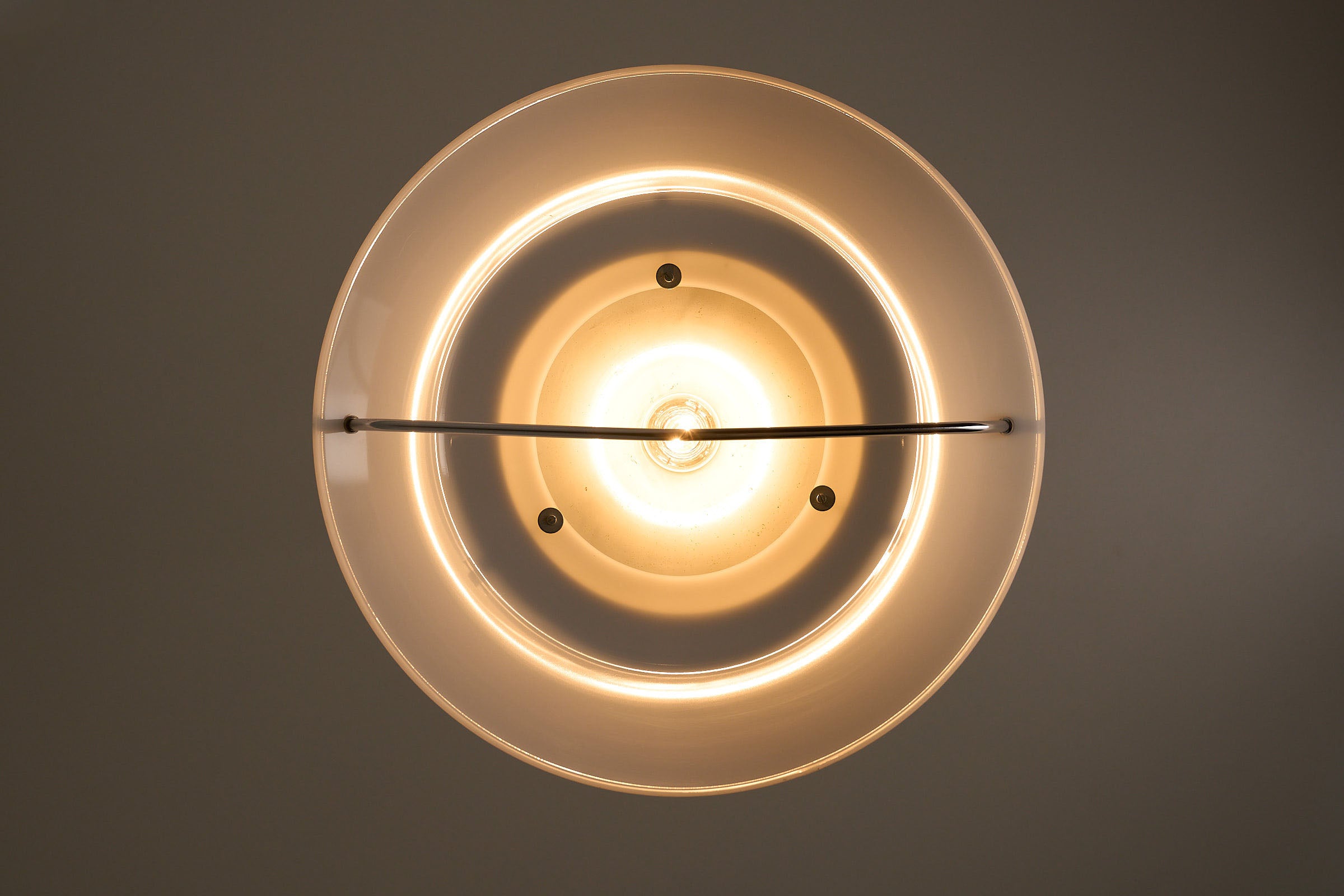 Mid-Century Modern White Acrylic Dish Pendant with Chrome Yoke providing ambient lighting.