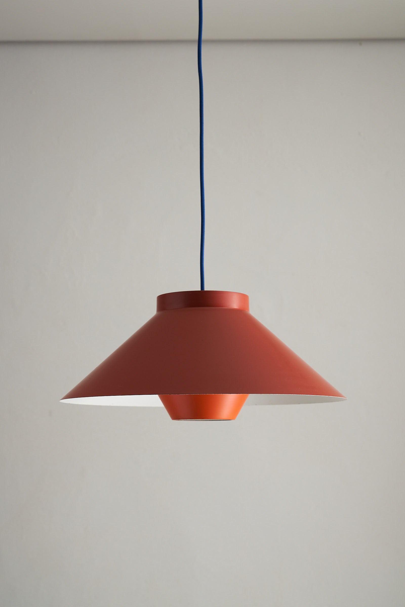 1960s Functionalist Layered Pendant Lamp in Stone Red hanging from the ceiling with a matte finish and conical design.