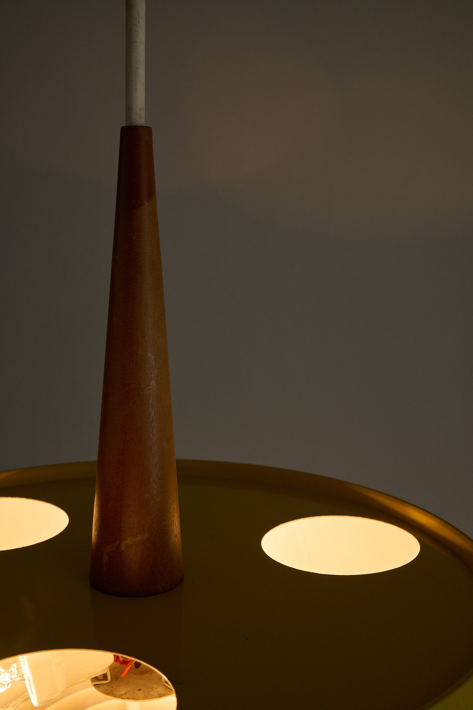 Pendant Lamp in Yellow with Teak Accent showcasing a warm Teak wood stem and ambient uplighting.