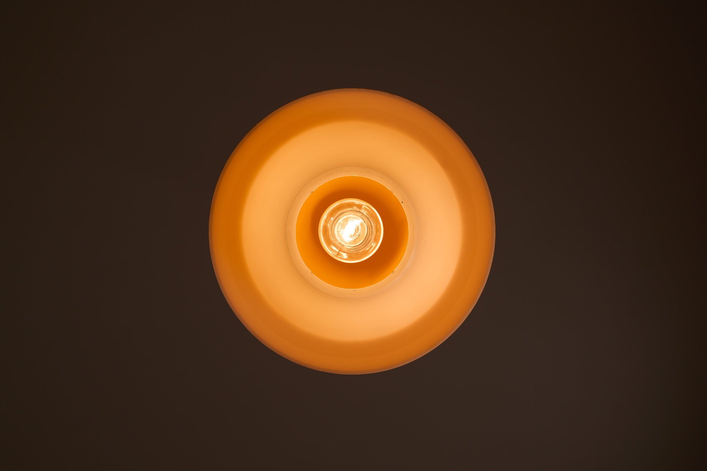 Space Age Mushroom Pendant in Yellow-Orange, ceiling light with layered design and warm, filtered light.