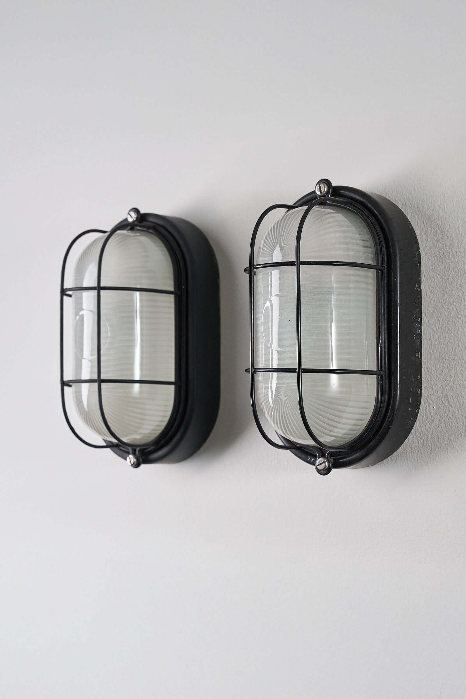 Set of 2 Black Flush-Mount Oval Cage Lamp mounted on a wall showing industrial design and glass diffuser.