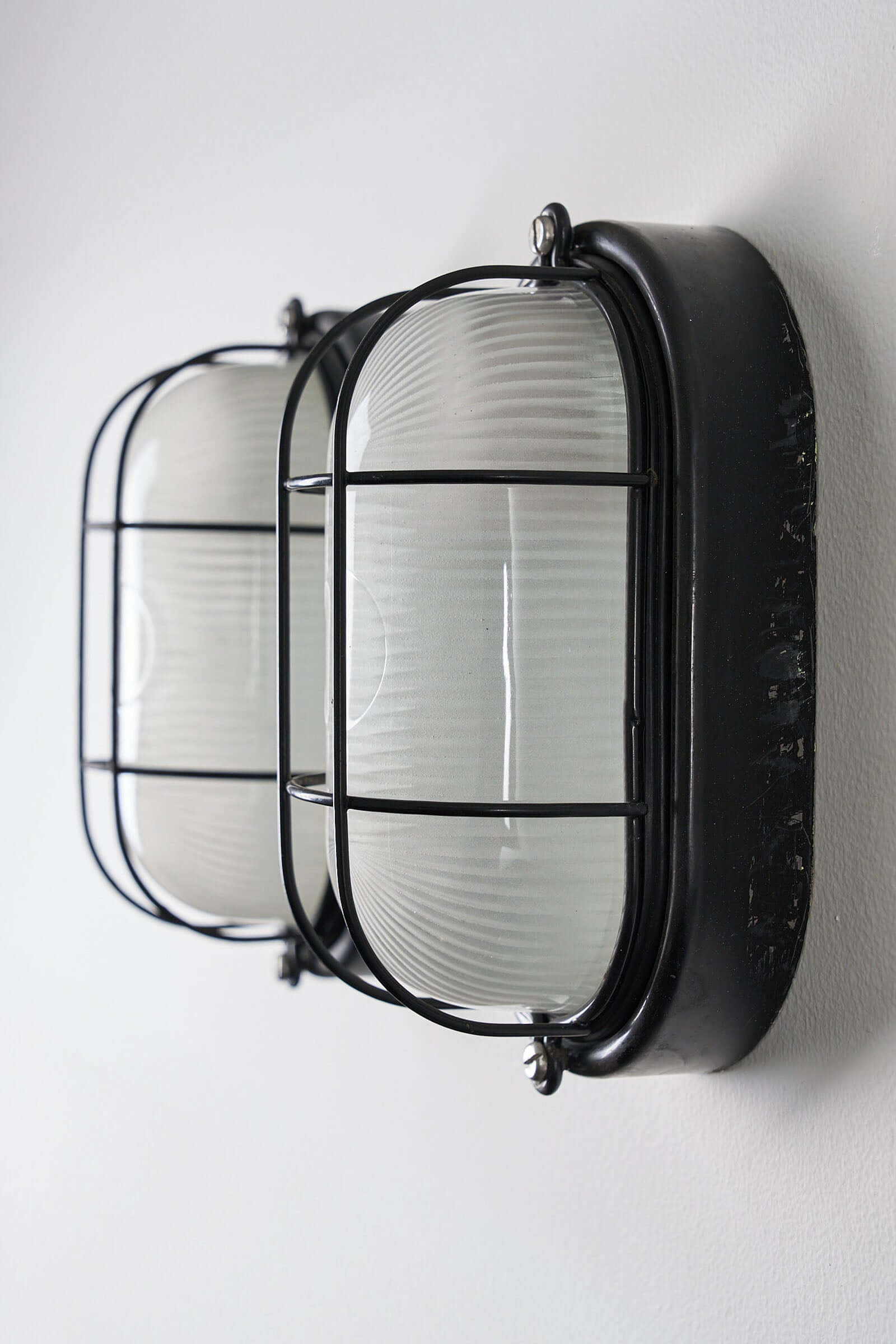 Set of 2 Black Flush-Mount Oval Cage Lamp displayed on a wall, featuring glass diffusers and a vintage industrial design.