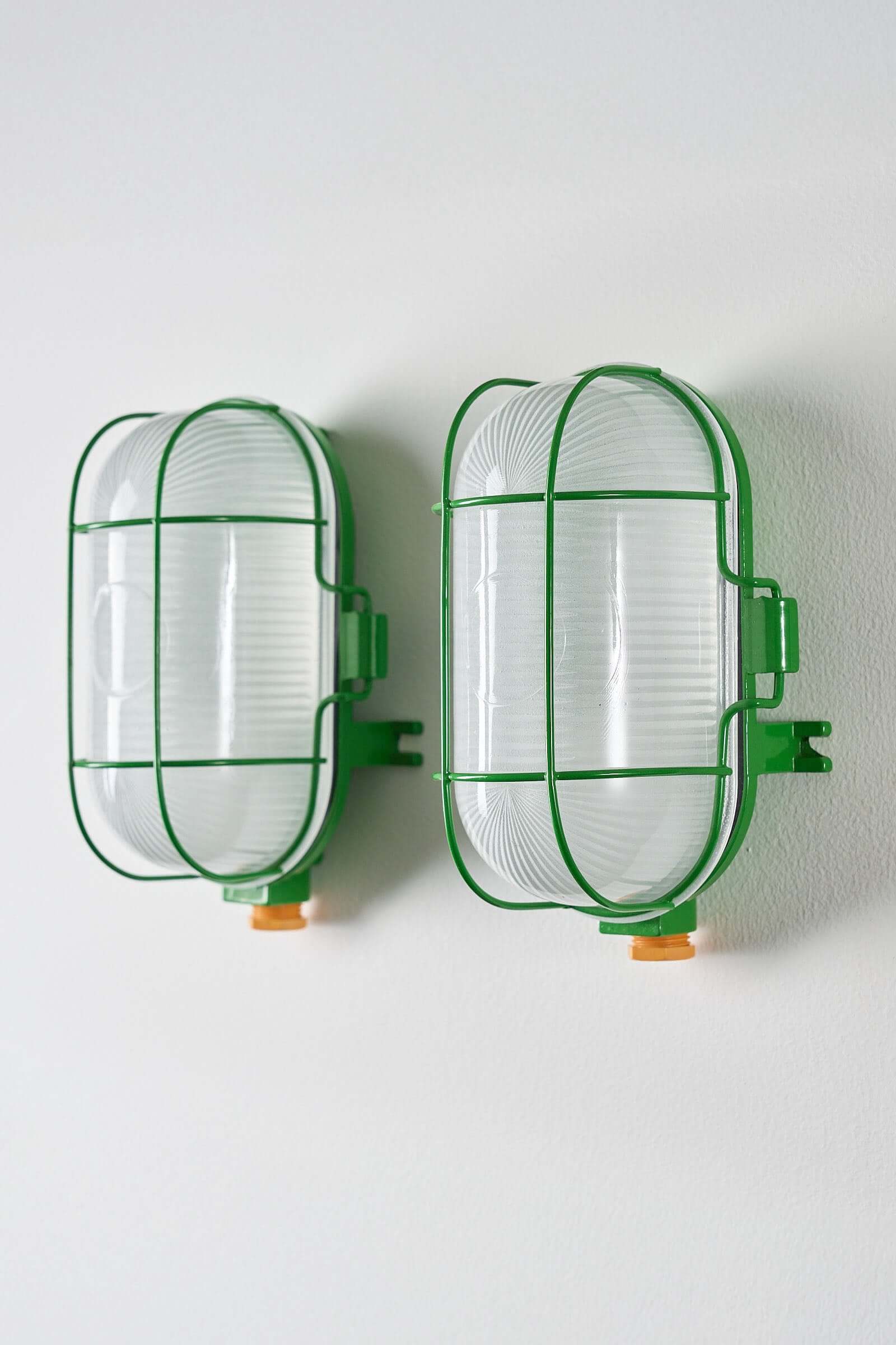 Set of 2 Industrial Oval Bright Green Cage Lamp mounted on a wall, showcasing bright green wire cages and glass diffusers.
