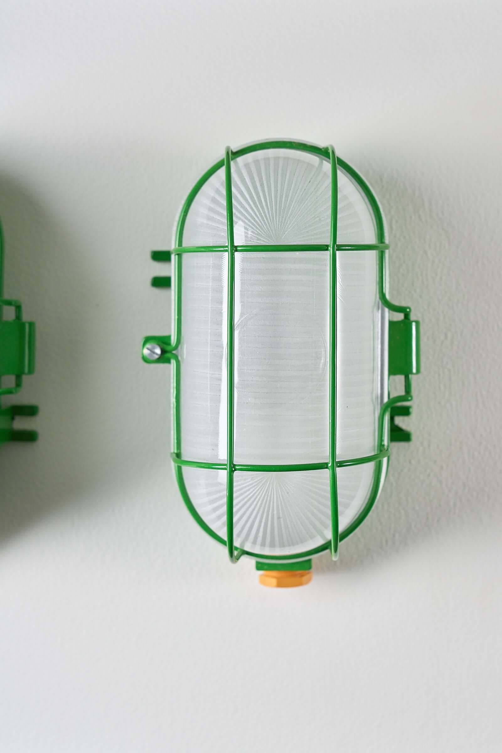 Set of 2 Industrial Oval Bright Green Cage Lamp mounted on a wall with a thick glass diffuser and green wire cage.