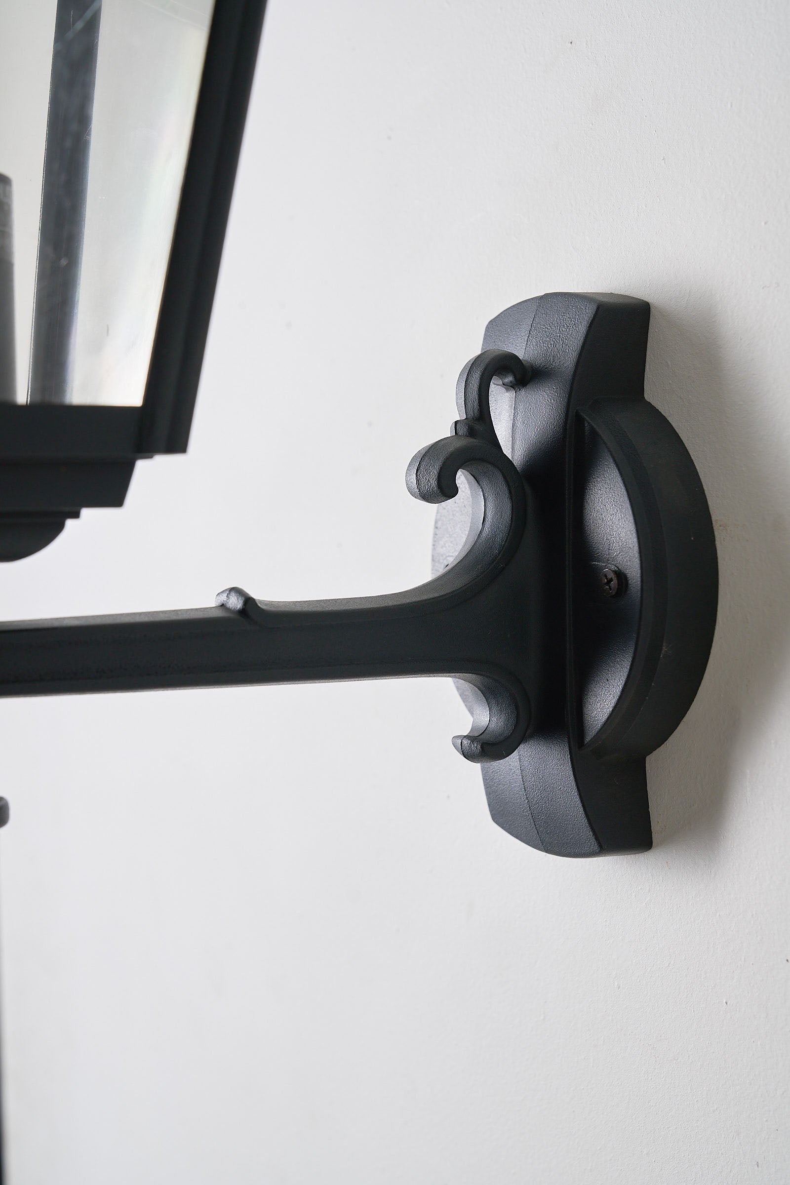 Traditional Outdoor Wall Lantern by Lothus mounted on a wall, showcasing black lacquered metal design for outdoor lighting.