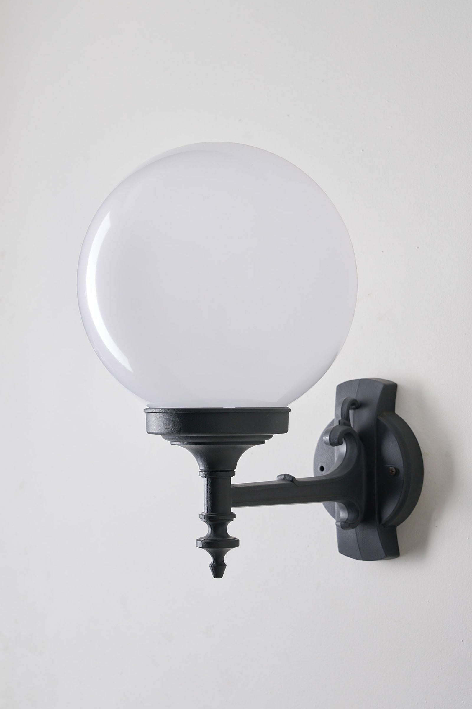 Traditional Outdoor Spherical Wall Lamp by Lothus mounted on a wall, featuring a translucent globe and black bracket.