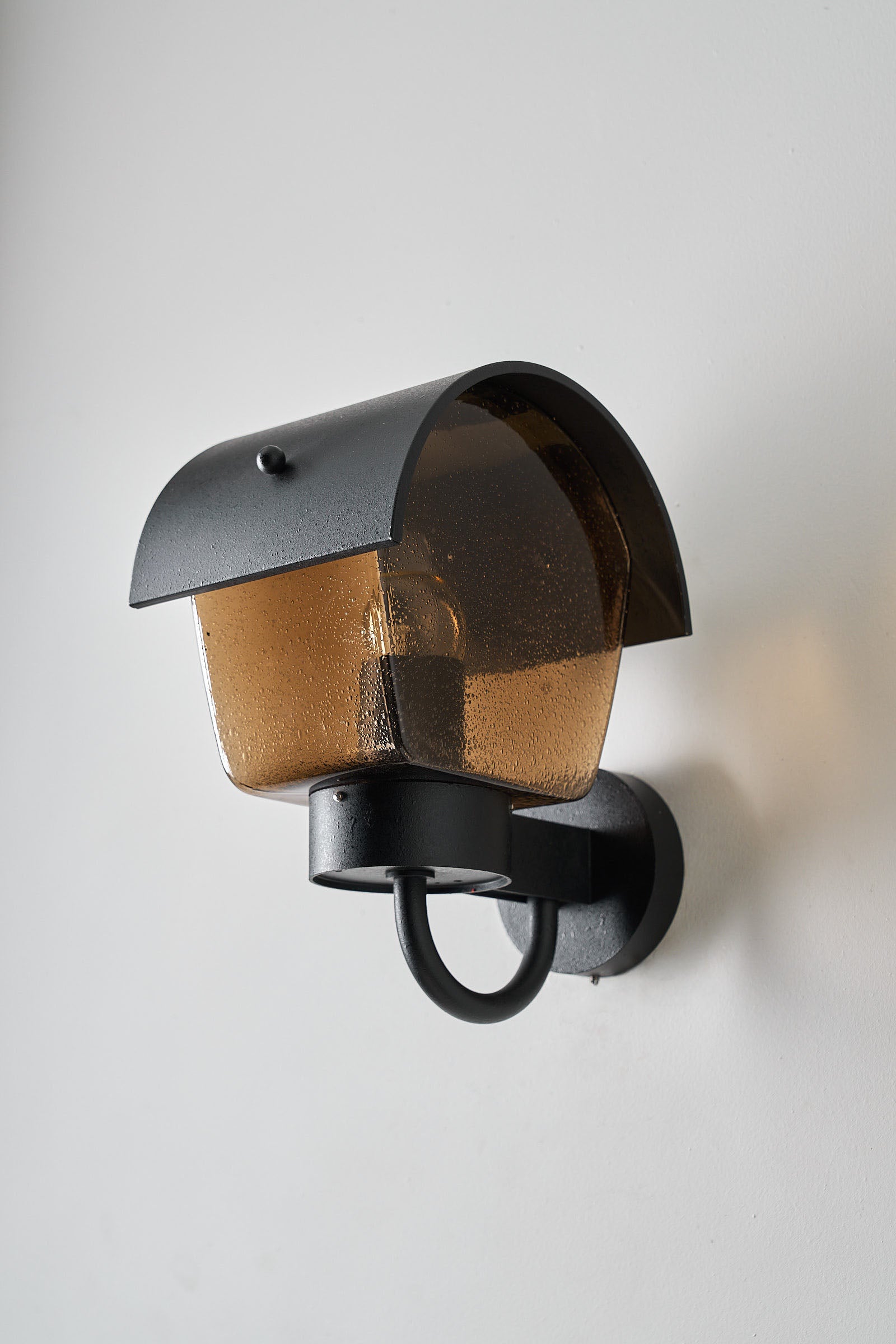 Outdoor Wall Light Amber Bubble Glass and Metal Hood mounted on a wall, showcasing its unique design and exterior lighting features.