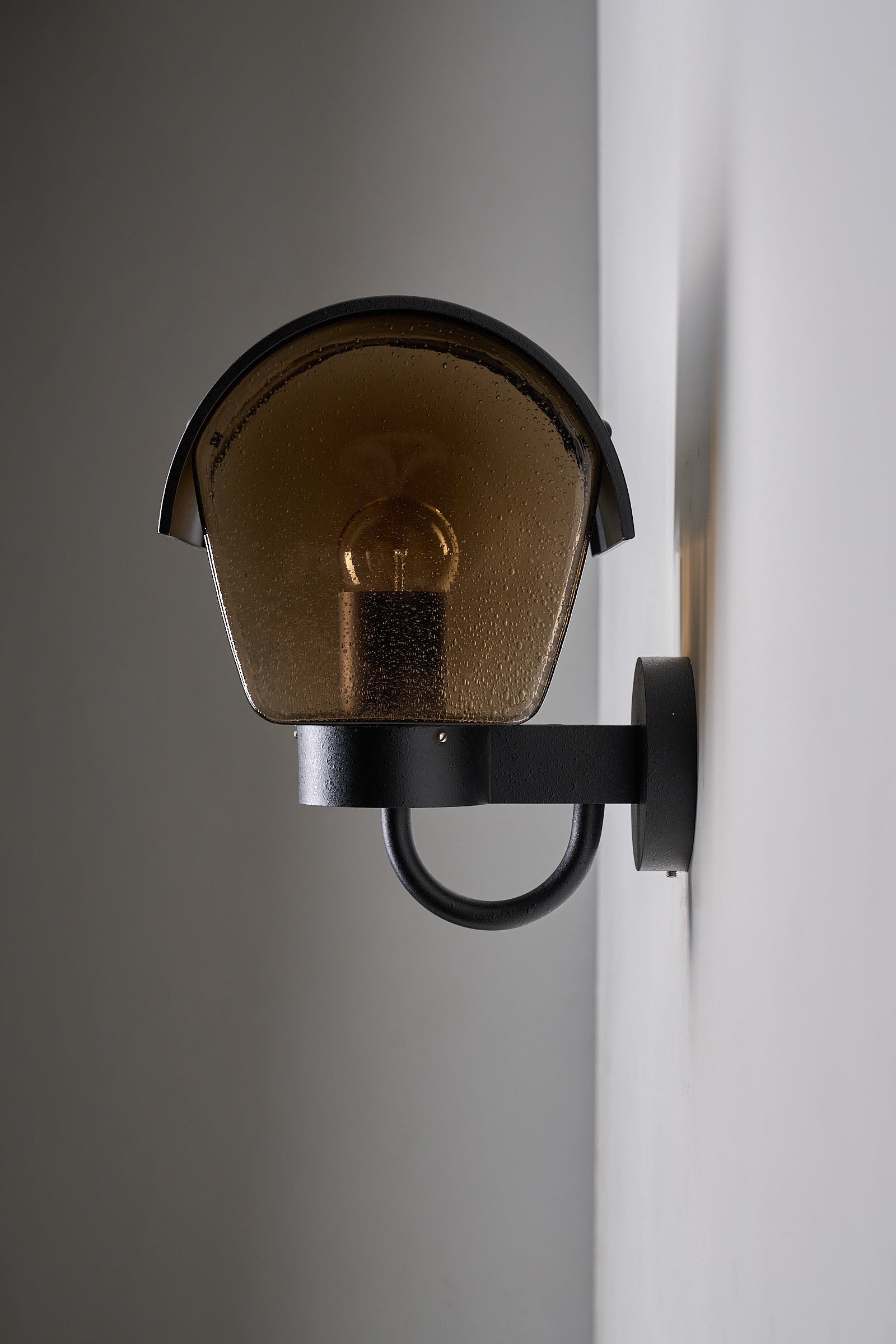 Outdoor Wall Light Amber Bubble Glass and Metal Hood mounted on a wall, showcasing warm light and durable design.