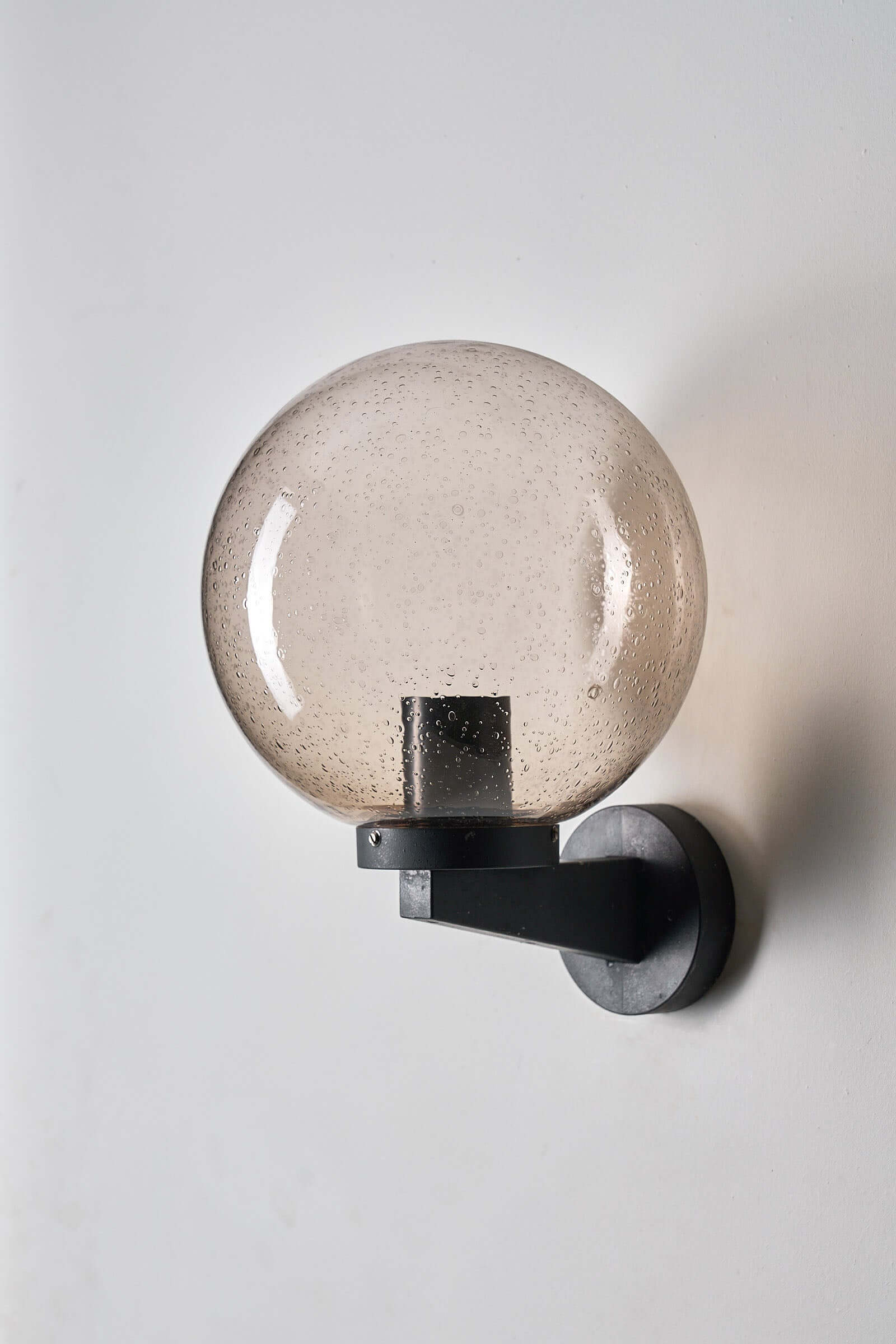 Outdoor Glass Globe Wall Light by Bega Boom mounted on wall with amber tinted spherical glass.