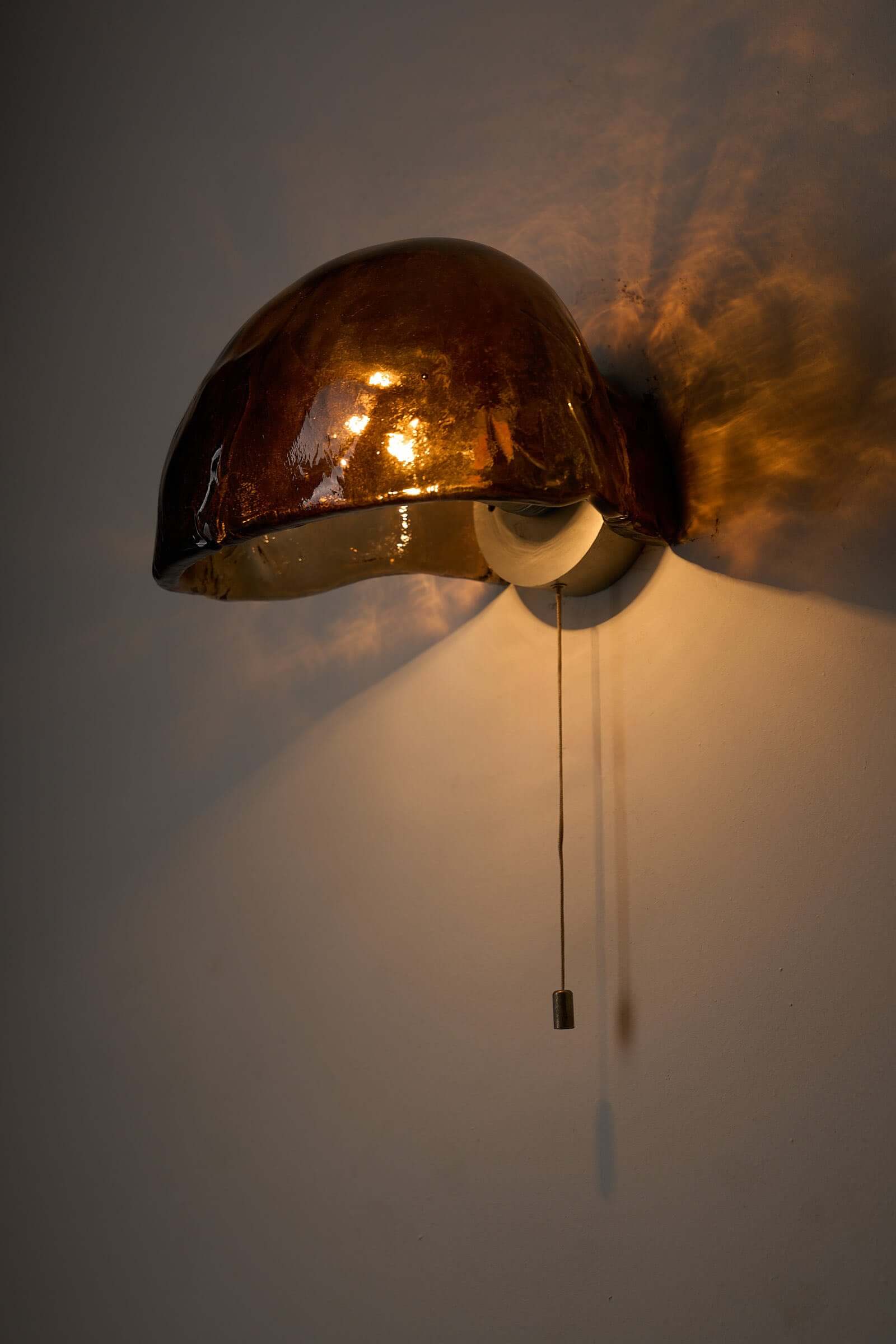 Pair of Kalmar Brown Glass Wall Lamps illuminating a wall with warm amber light.