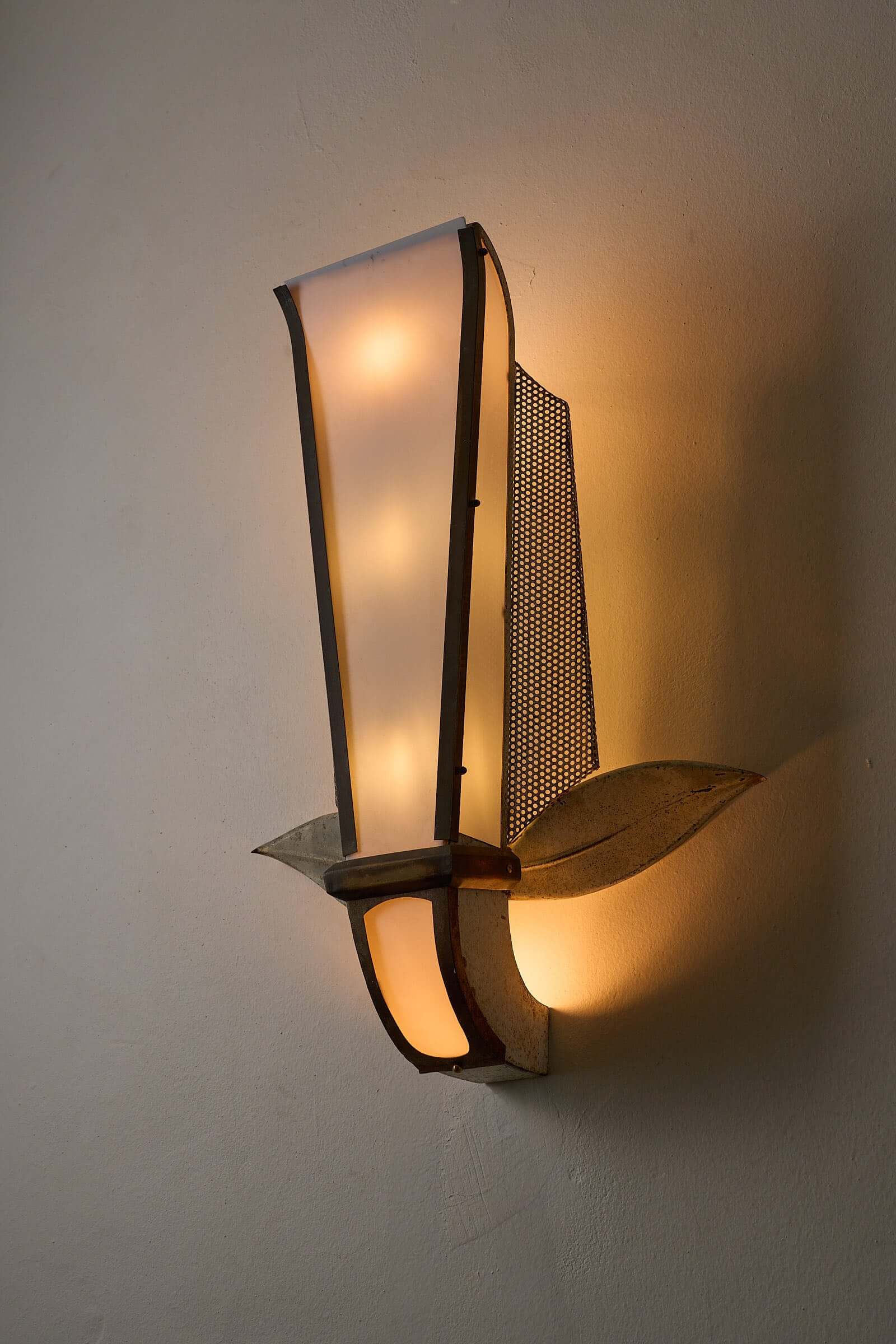 Grand Parisian Art Deco Wall Sconce with perforated metal and leaf accents, illuminating a stylish interior.