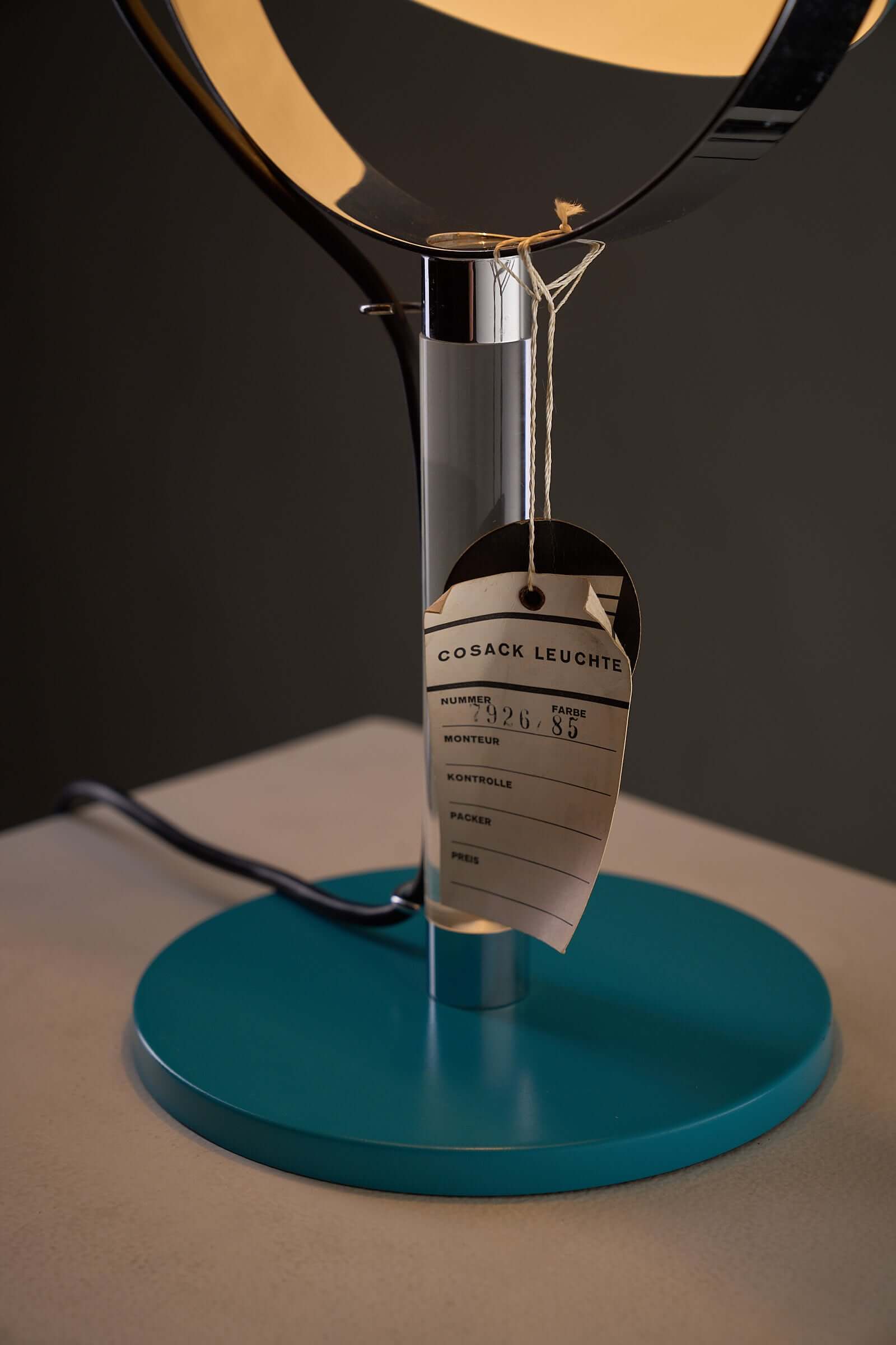 Close-up of Turquoise Desk Lamp with Acrylic Stem by Cosack, showing tag and base details.