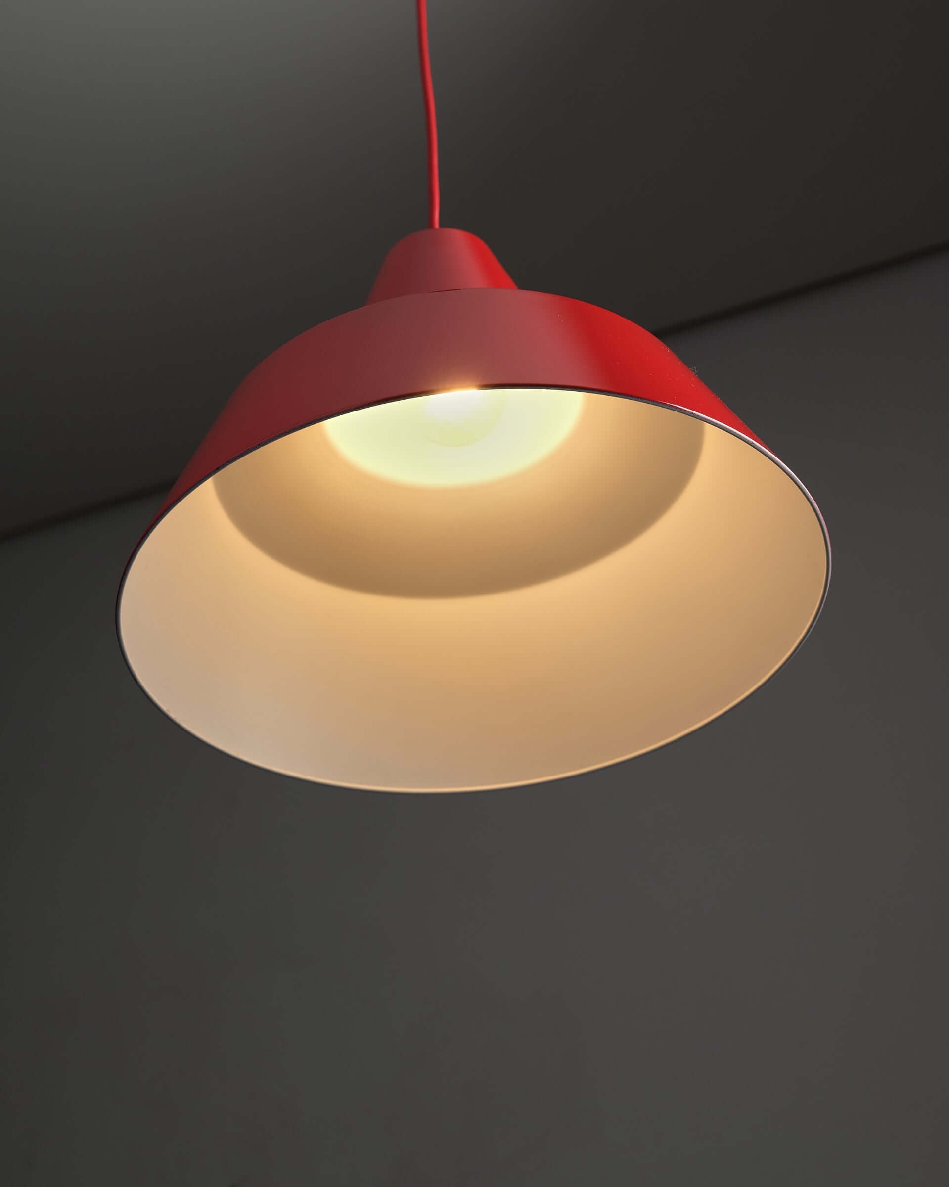 Red Industrial Warehouse Pendant Light by Lyfa hanging with a glossy red shade and white interior for bright illumination.
