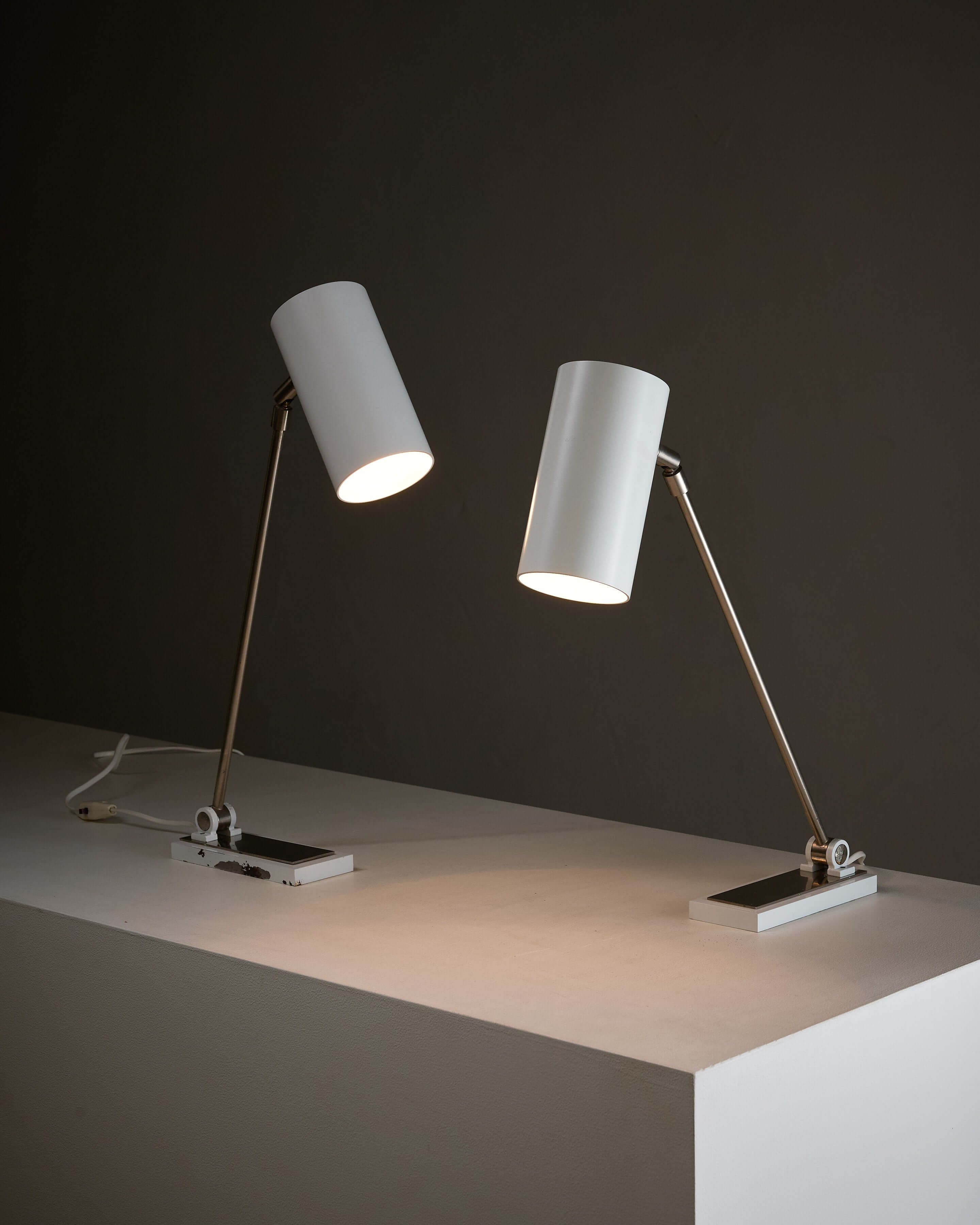 Minimalist White Cylinder Desk Lamp by Artiforte on a modern table with a dark background, showcasing adjustable design.