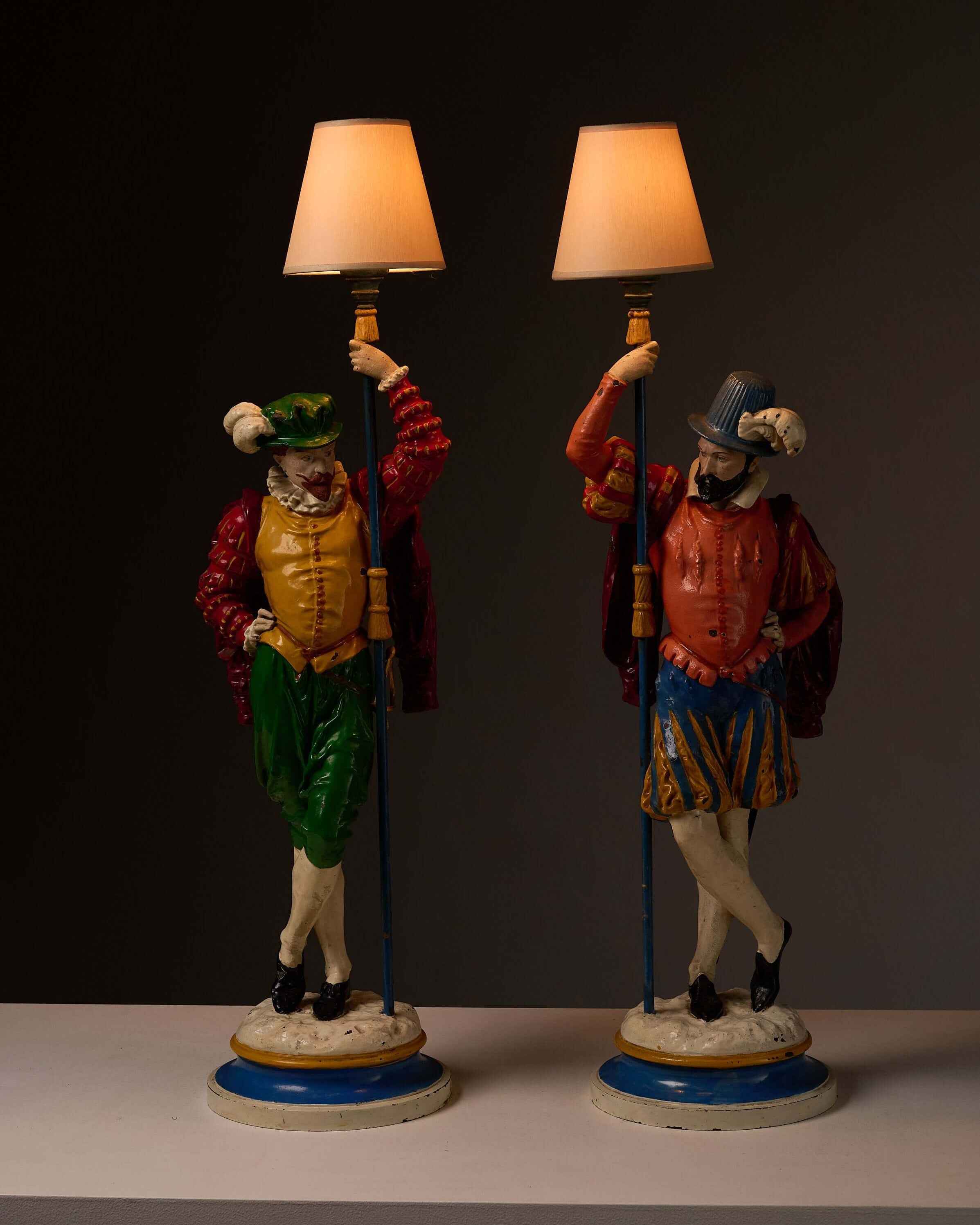 Pair of Painted Cast Iron Guard Figures Table Lamps standing with warm shades illuminating their colorful attire.