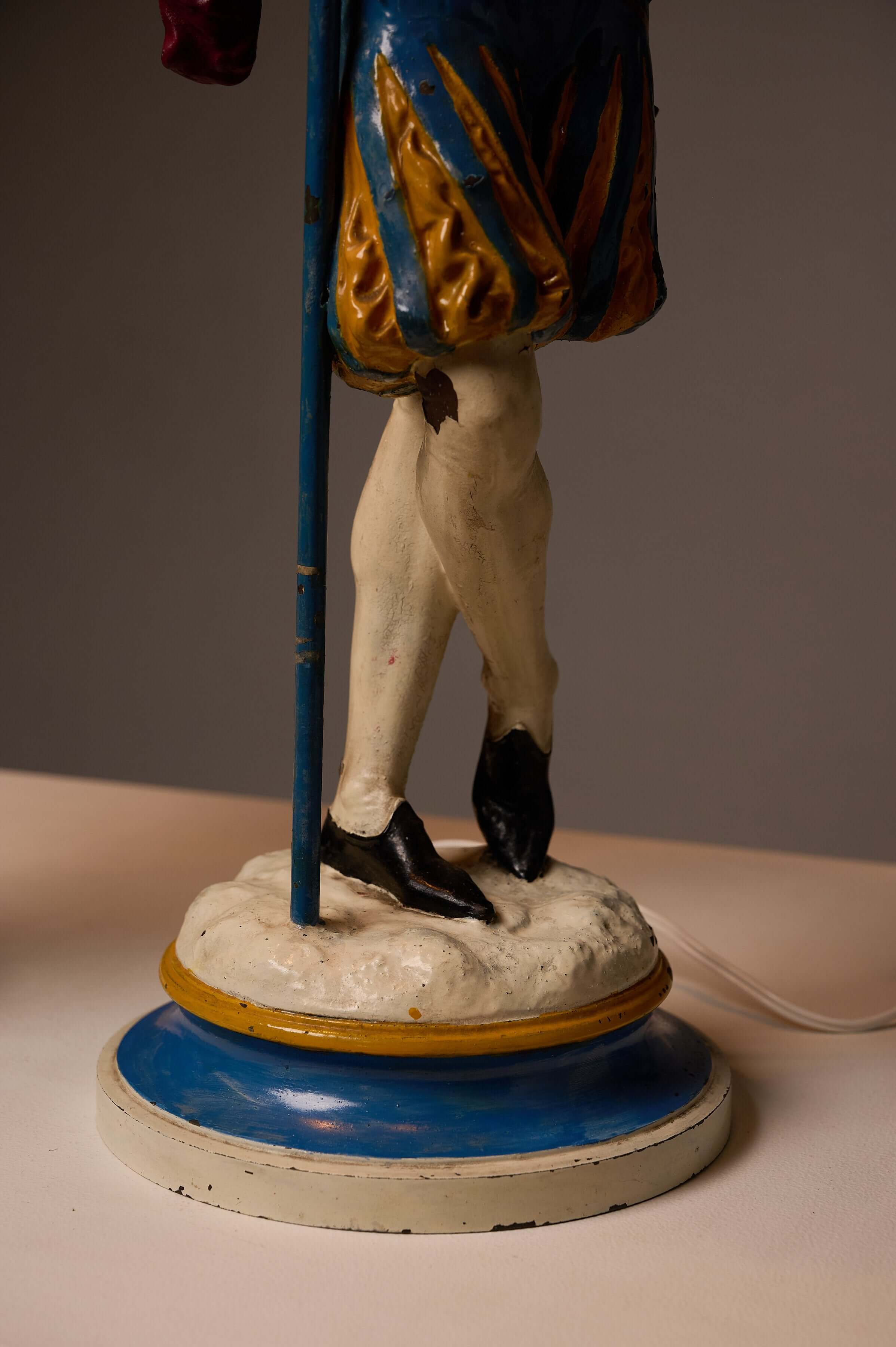 Detail of a leg from the Pair of Painted Cast Iron Guard Figures Table Lamps showcasing vibrant painted attire.