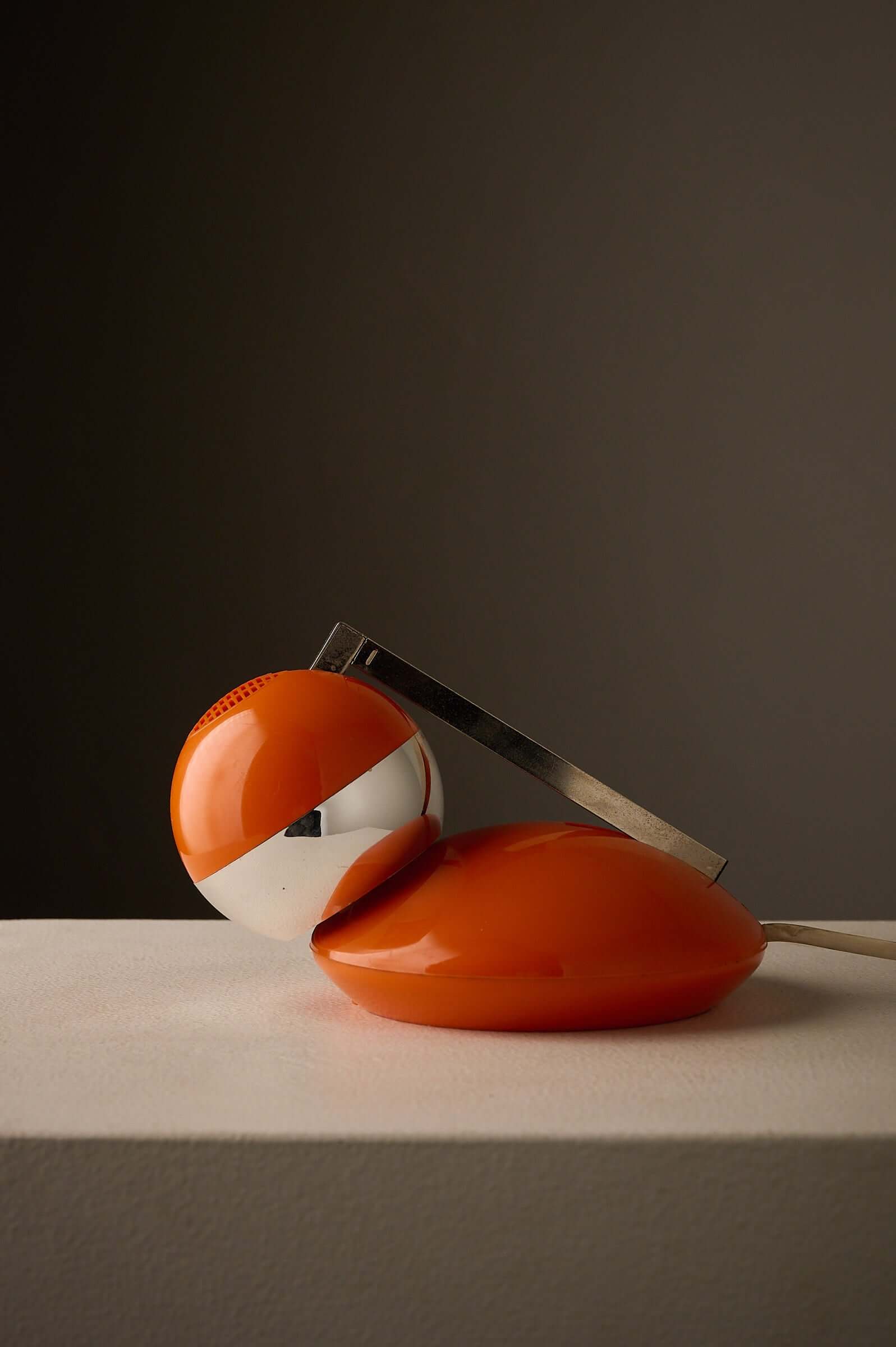 1970s Orange Pop Art Desk Lamp with a compact design and chrome arm against a dark background.