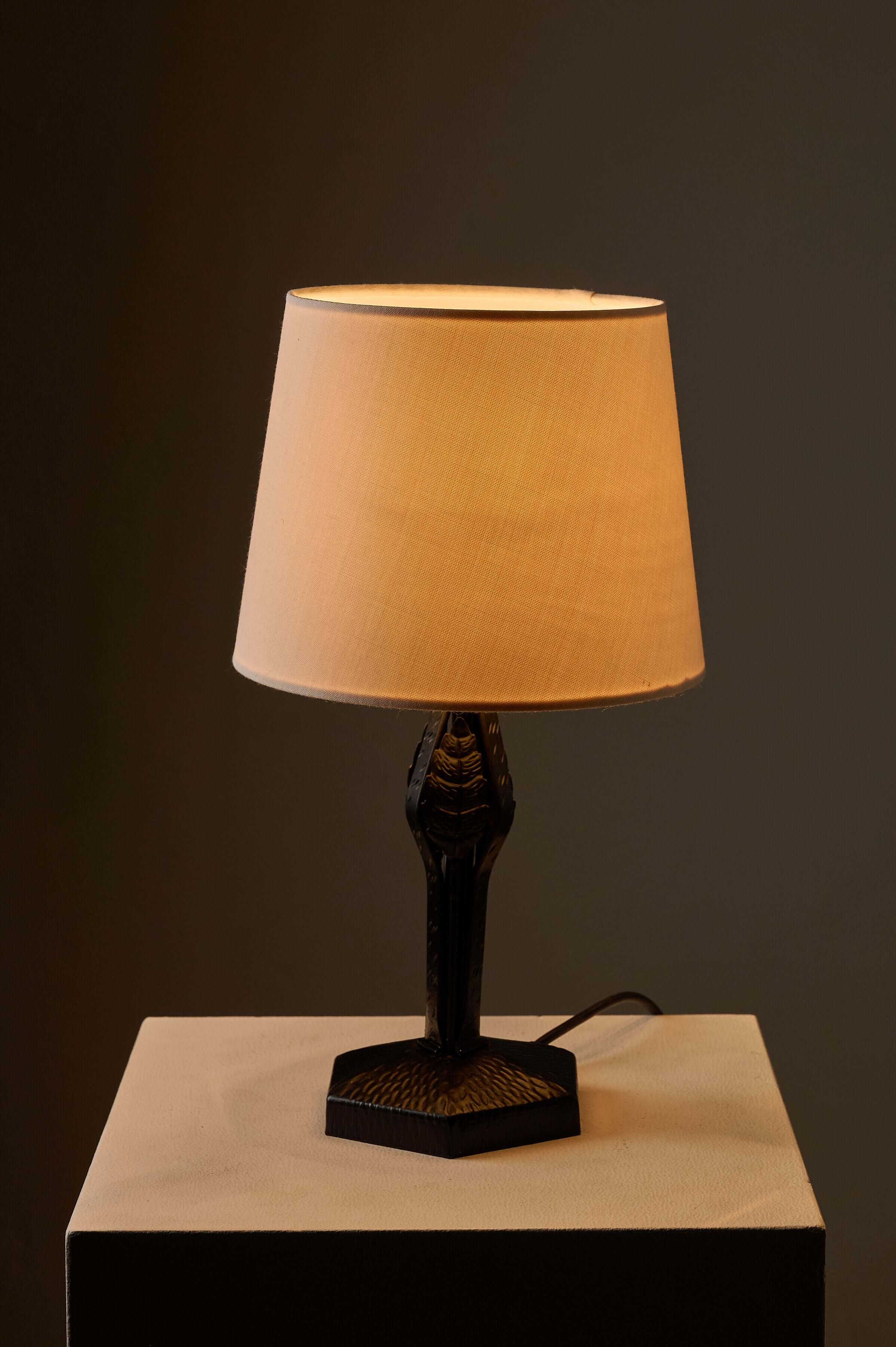 Black Hammered Metal Table Lamp with Stylized Leaf Motif on a hexagonal base, featuring a warm beige lampshade.