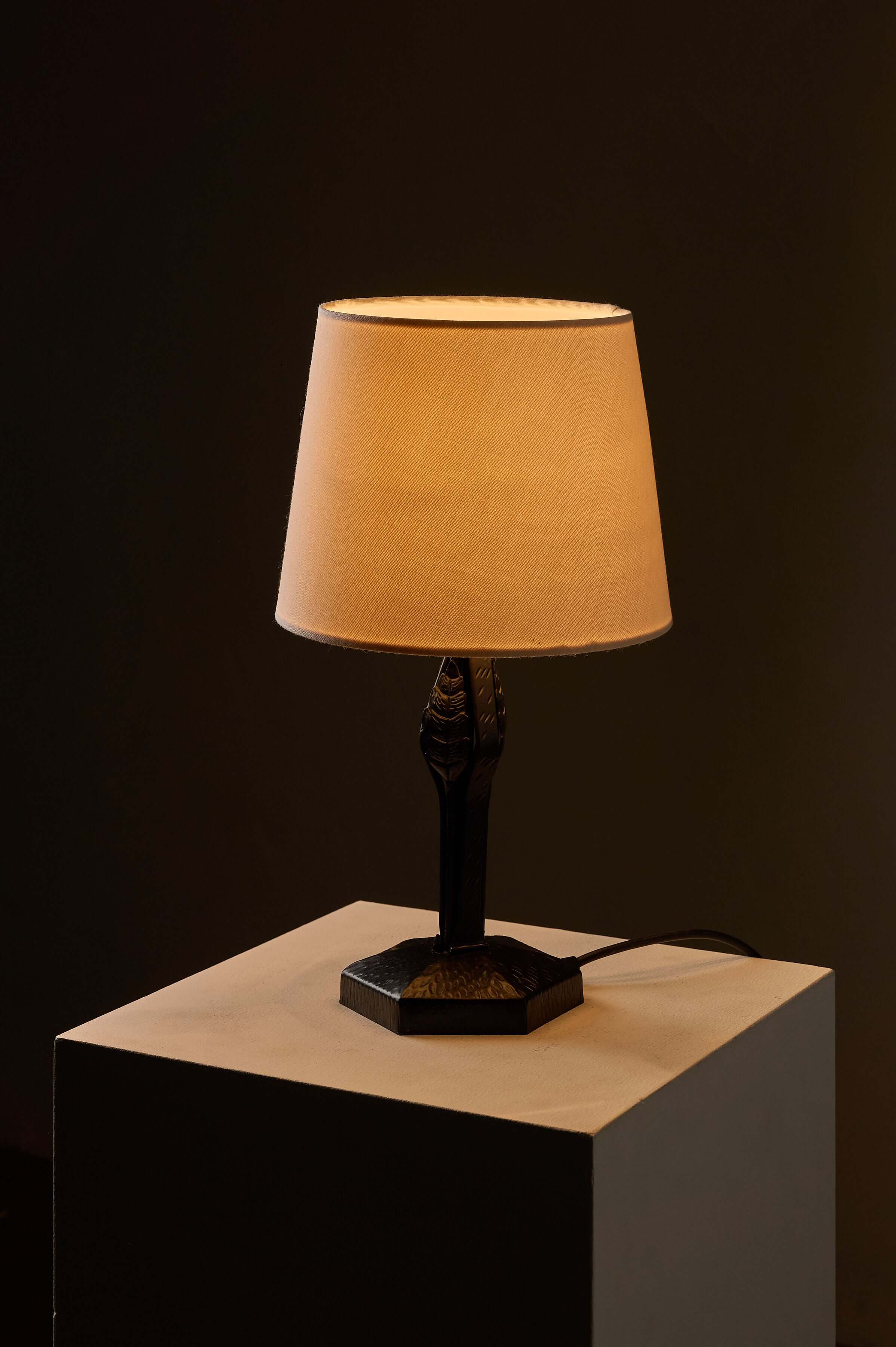 Black Hammered Metal Table Lamp with Stylized Leaf Motif on a pedestal in soft lighting.