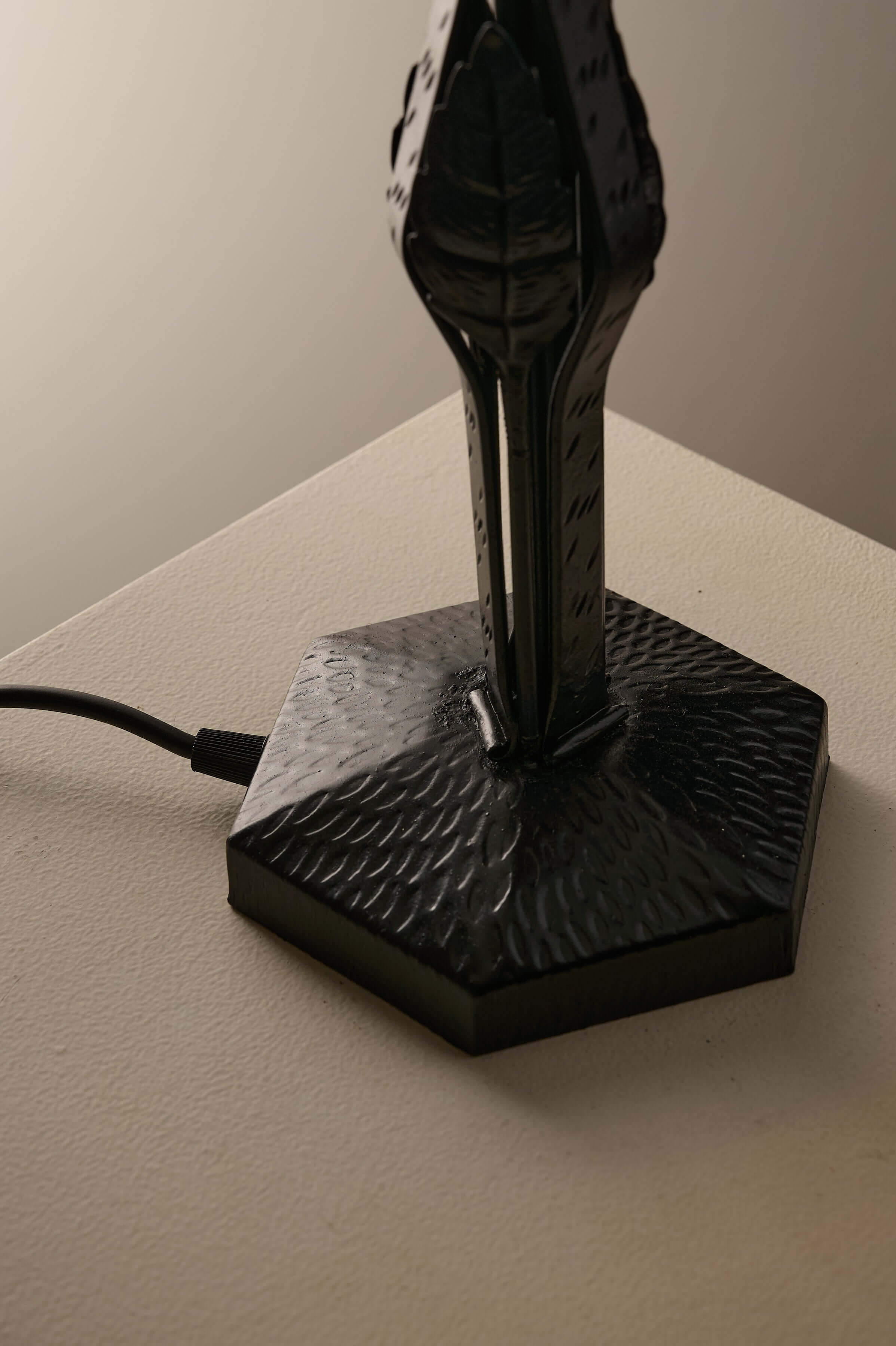 Black Hammered Metal Table Lamp with Stylized Leaf Motif showcasing hexagonal base and leaf design.
