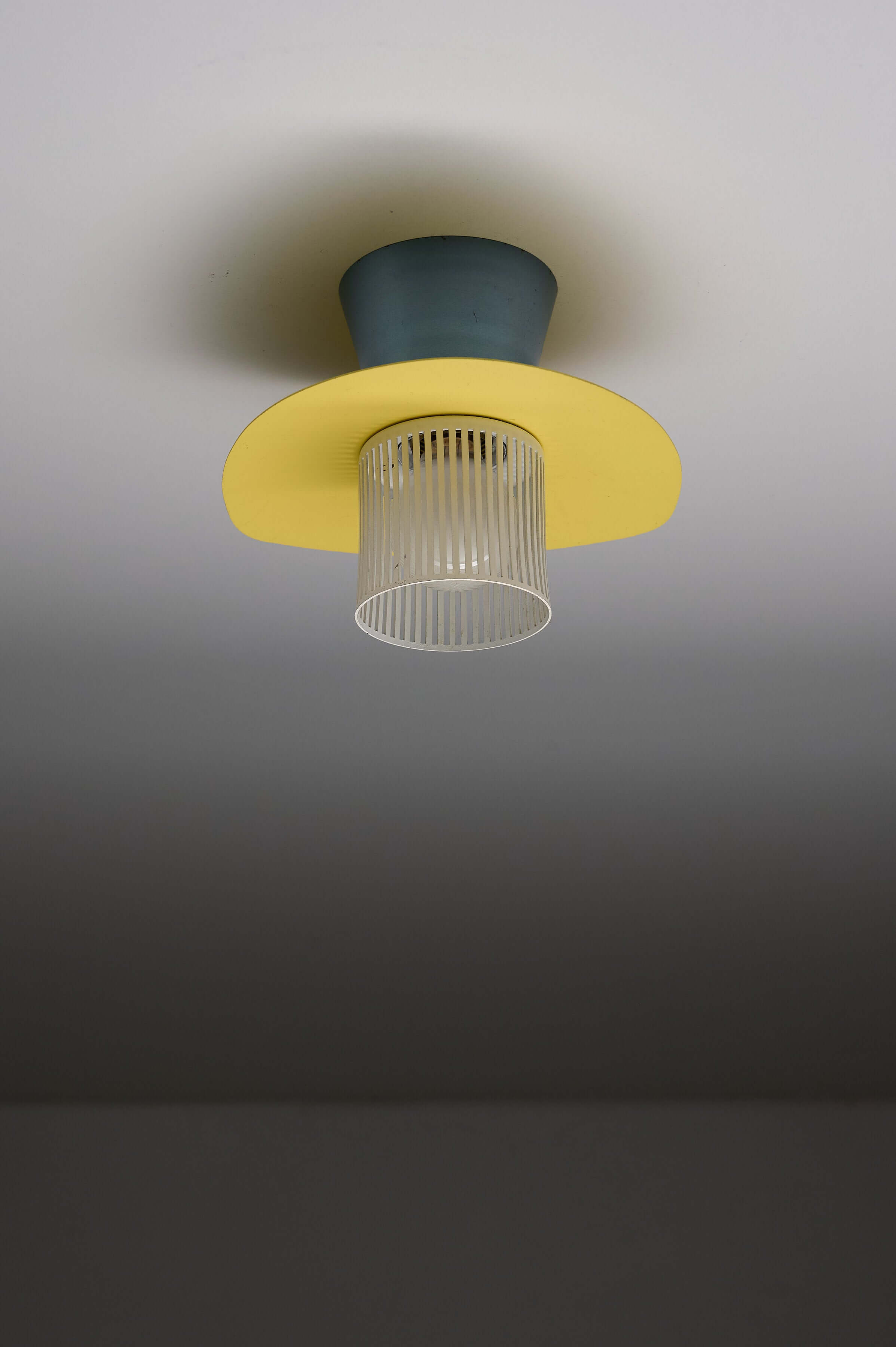 Mid-Century Plectrum Flush Mount in Yellow, Blue, and White hanging from a ceiling.