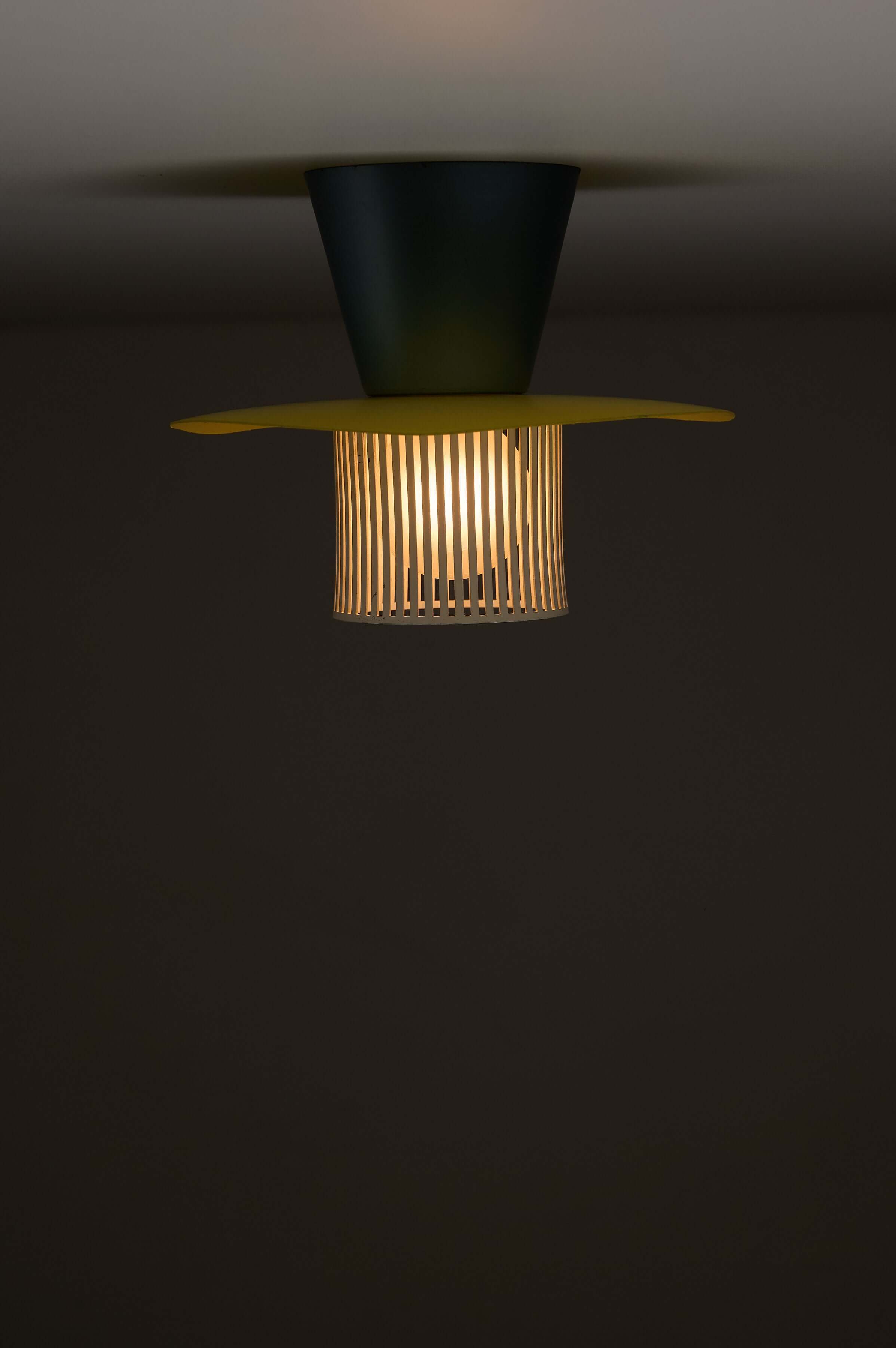 Mid-Century Plectrum Flush Mount in Yellow, Blue, and White illuminating a dark space.