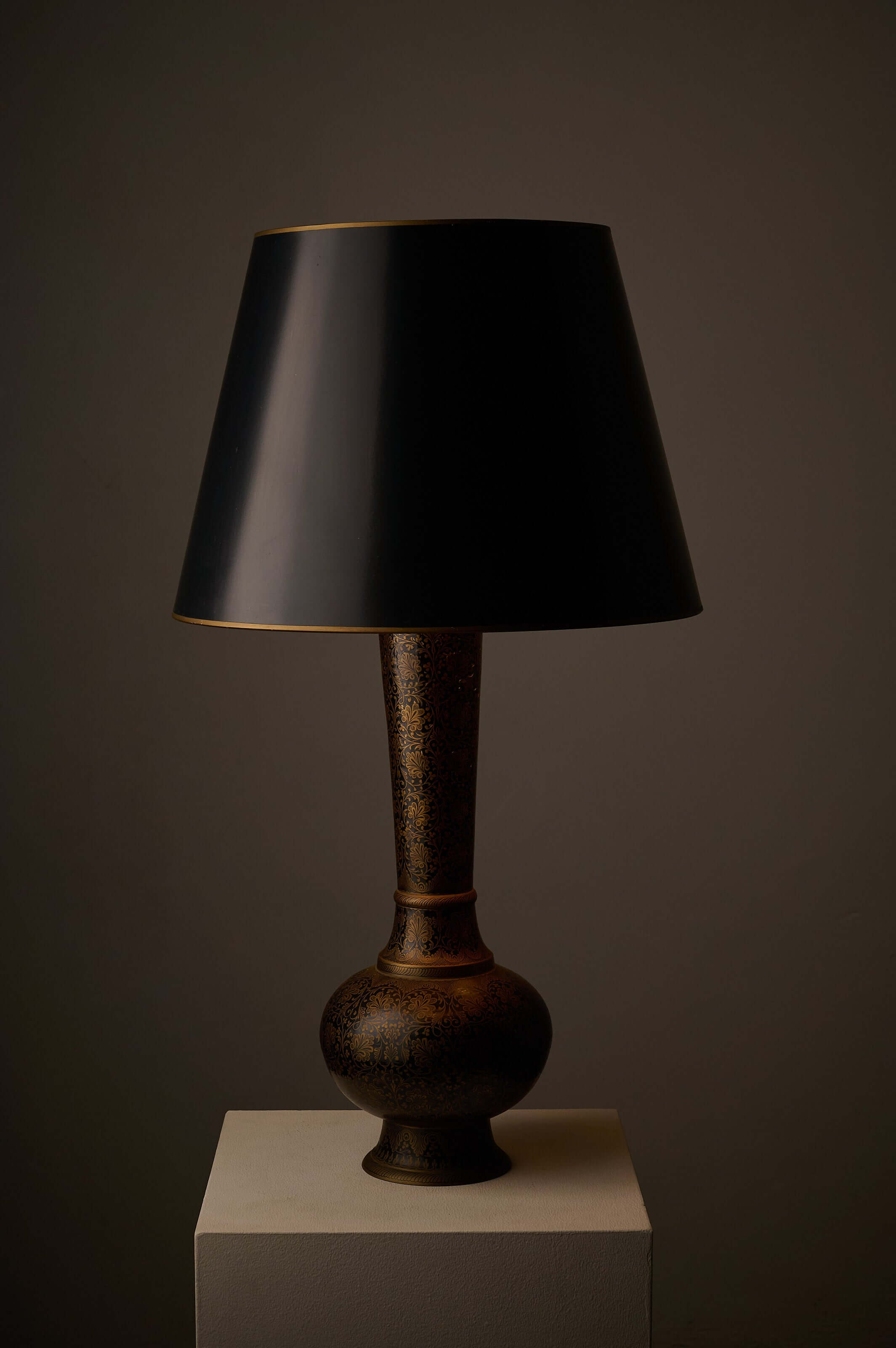 Tall Black and Gold Vase Lamp with Foliage Pattern on display with a black conical shade.