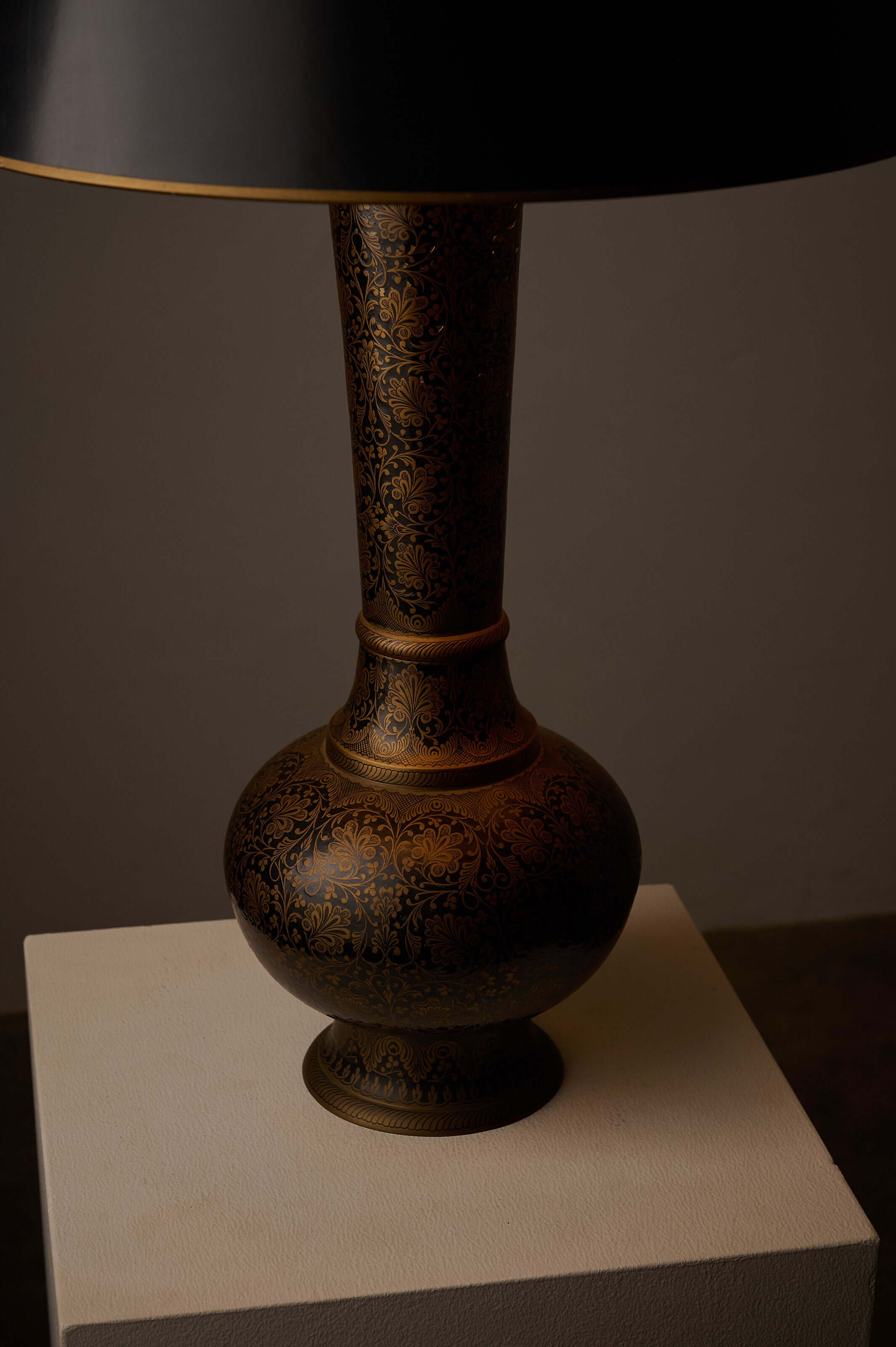 Tall Black and Gold Vase Lamp with Foliage Pattern on a side table, showcasing intricate floral pattern and black shade.