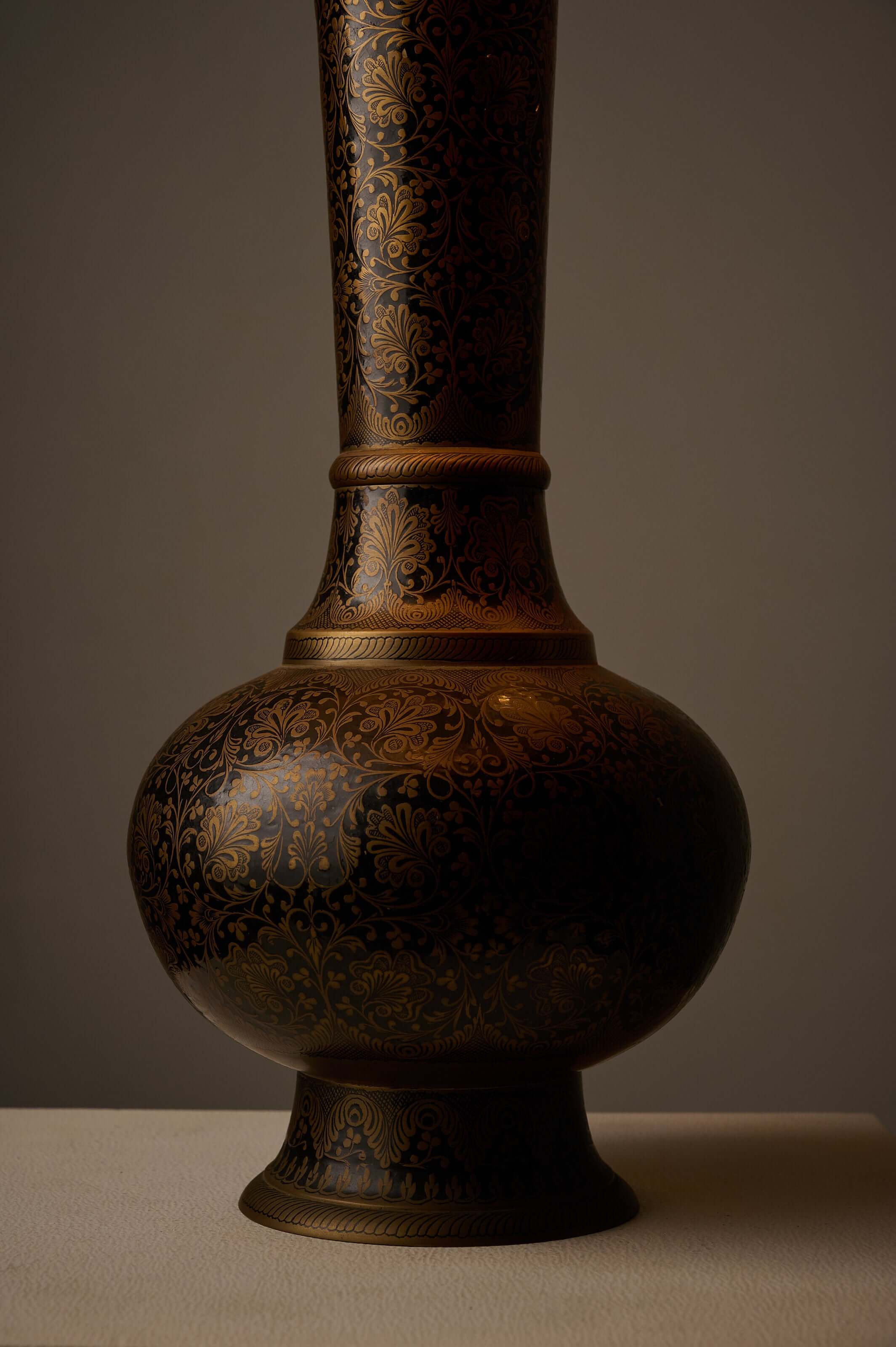 Tall Black and Gold Vase Lamp with Foliage Pattern showcasing intricate gold floral details on a black background.