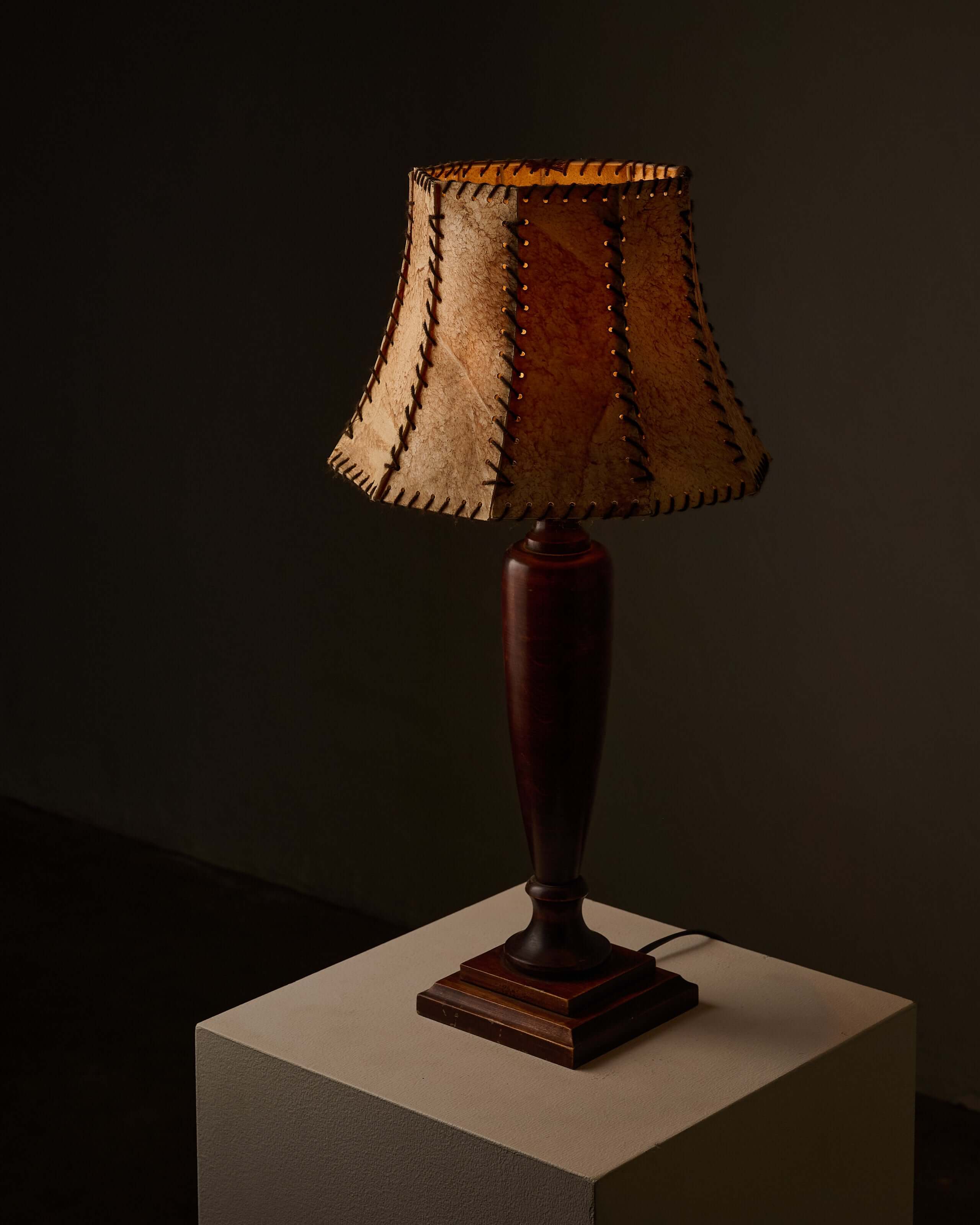 Turned dark wood table lamp with stitched shade showcasing rustic elegance and warm light.