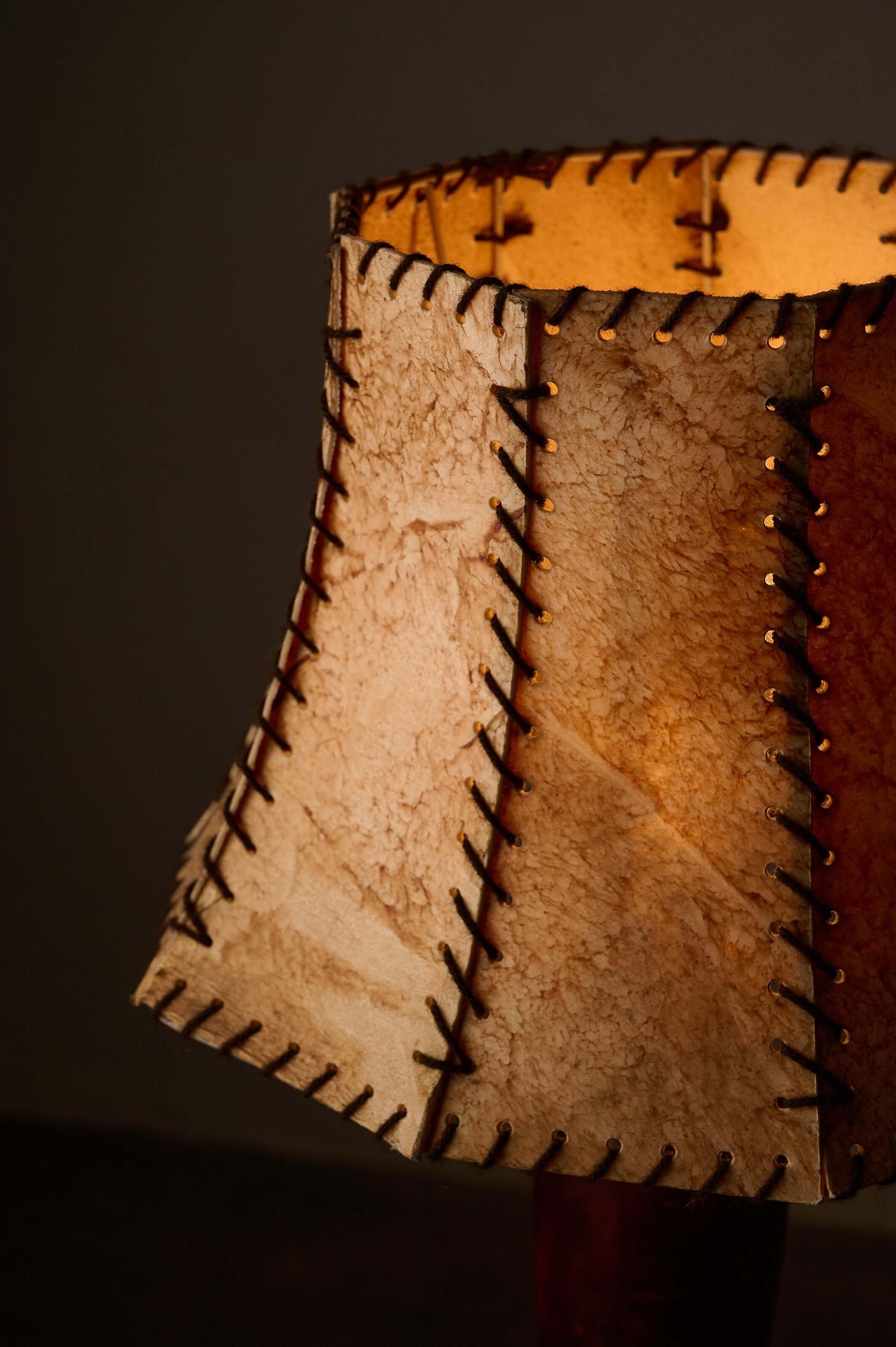 Turned dark wood table lamp with a hexagonal stitched shade highlighting warm light.