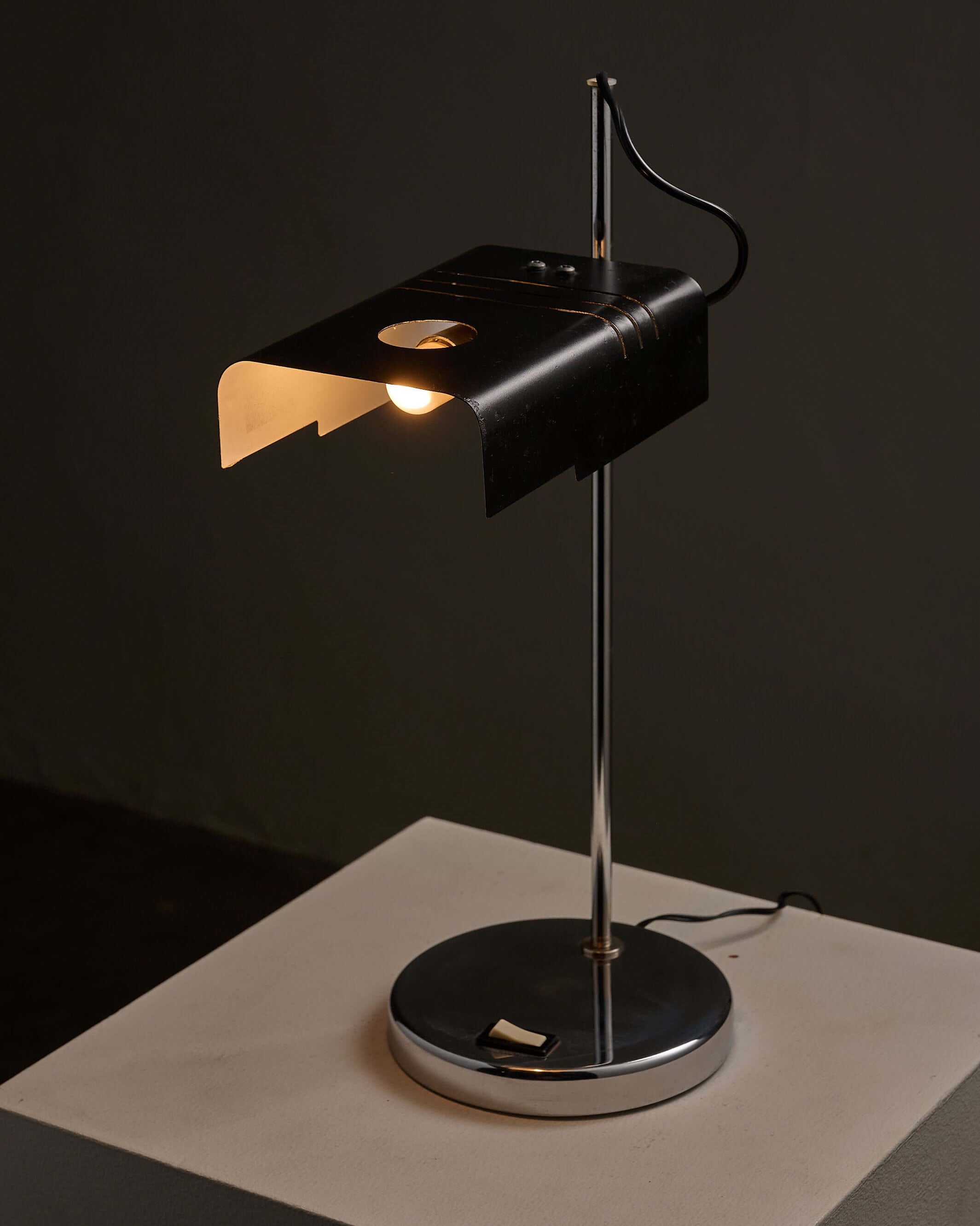 Adjustable chrome desk lamp showcasing minimalist design with black metal shade and chrome base.