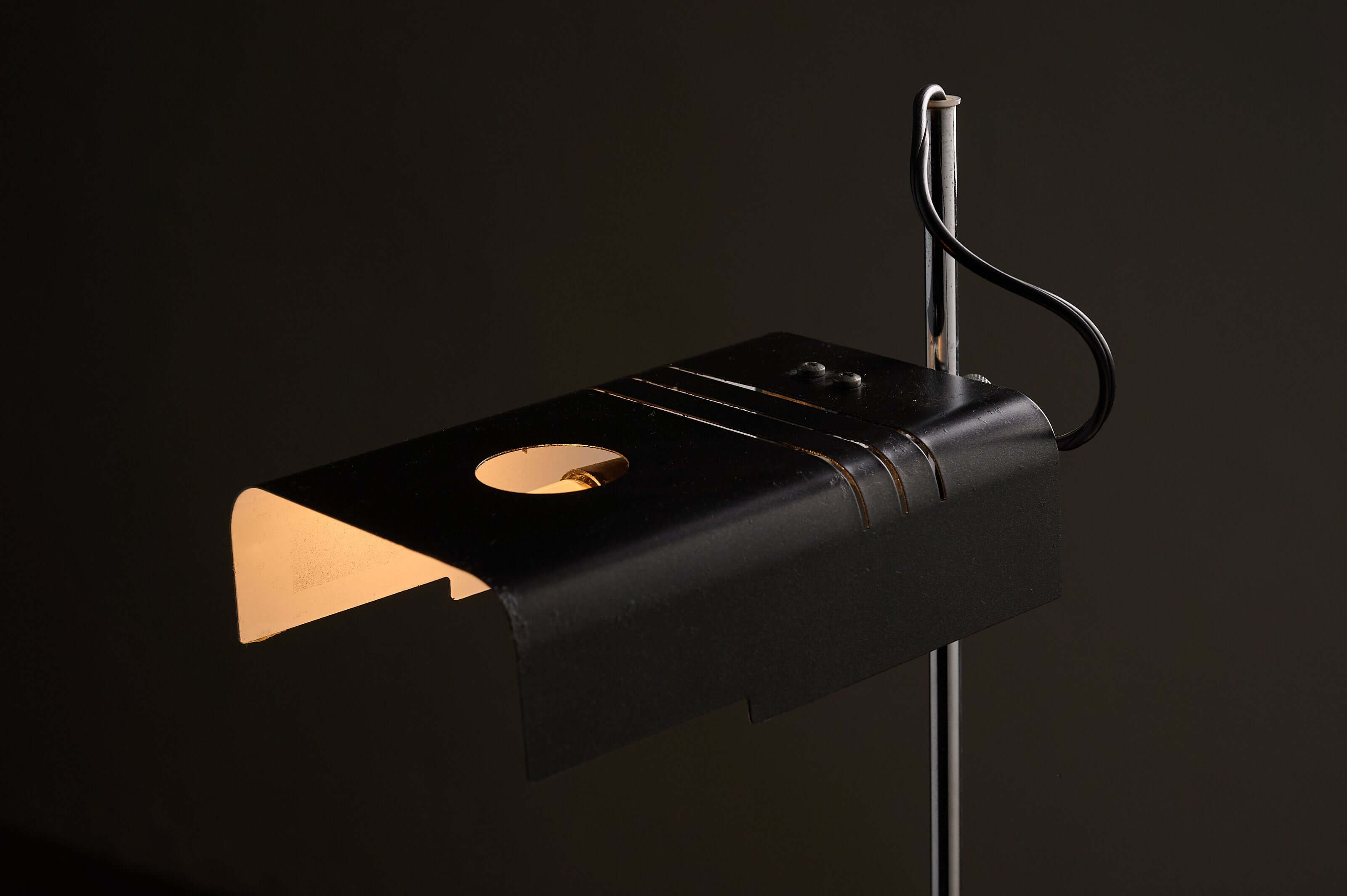 Adjustable chrome desk lamp featuring a folded black metal shade and a sleek tubular chrome stem.