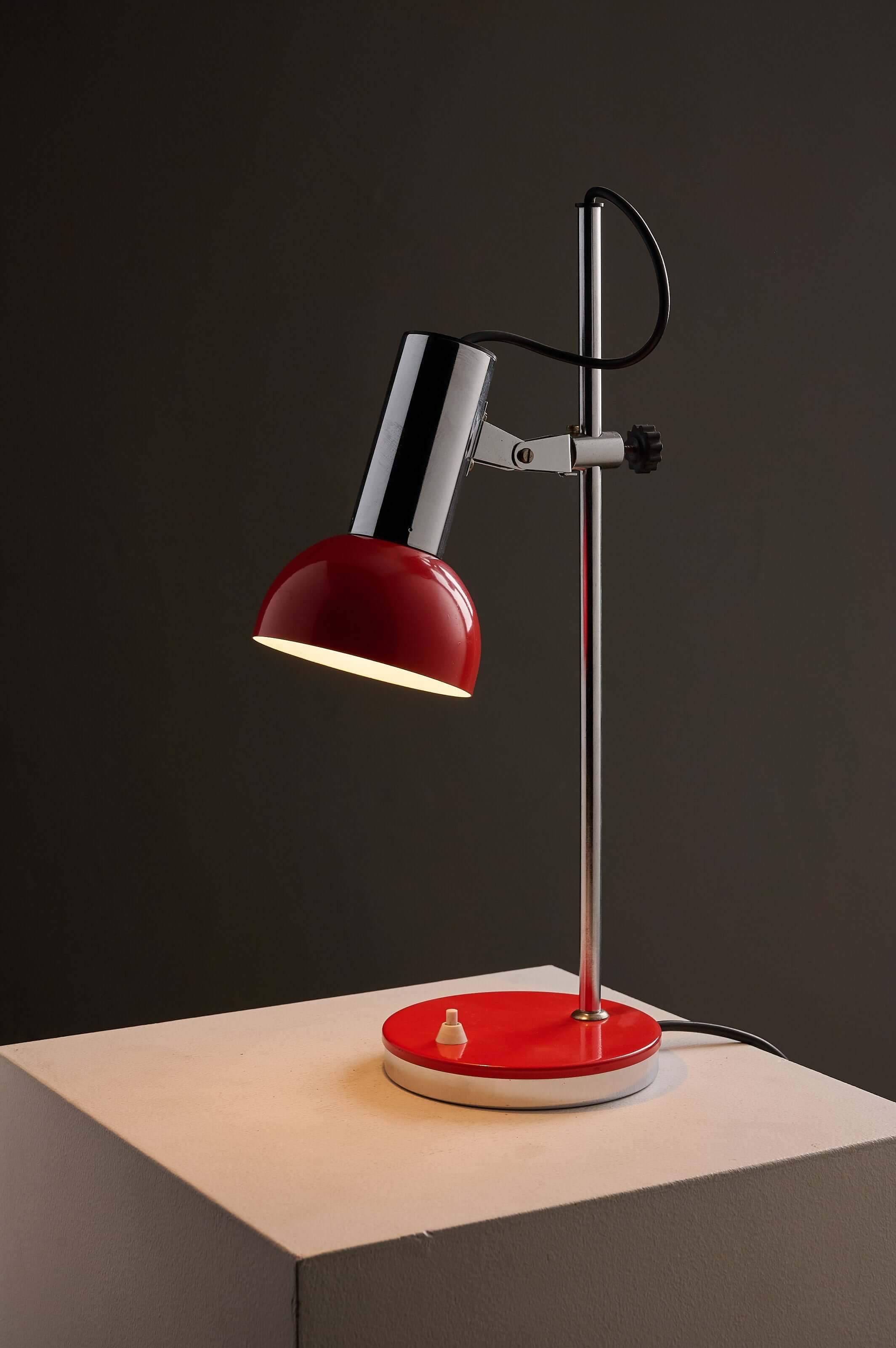 Adjustable chrome red table lamp featuring a bright red shade and weighted base, perfect for directing light.