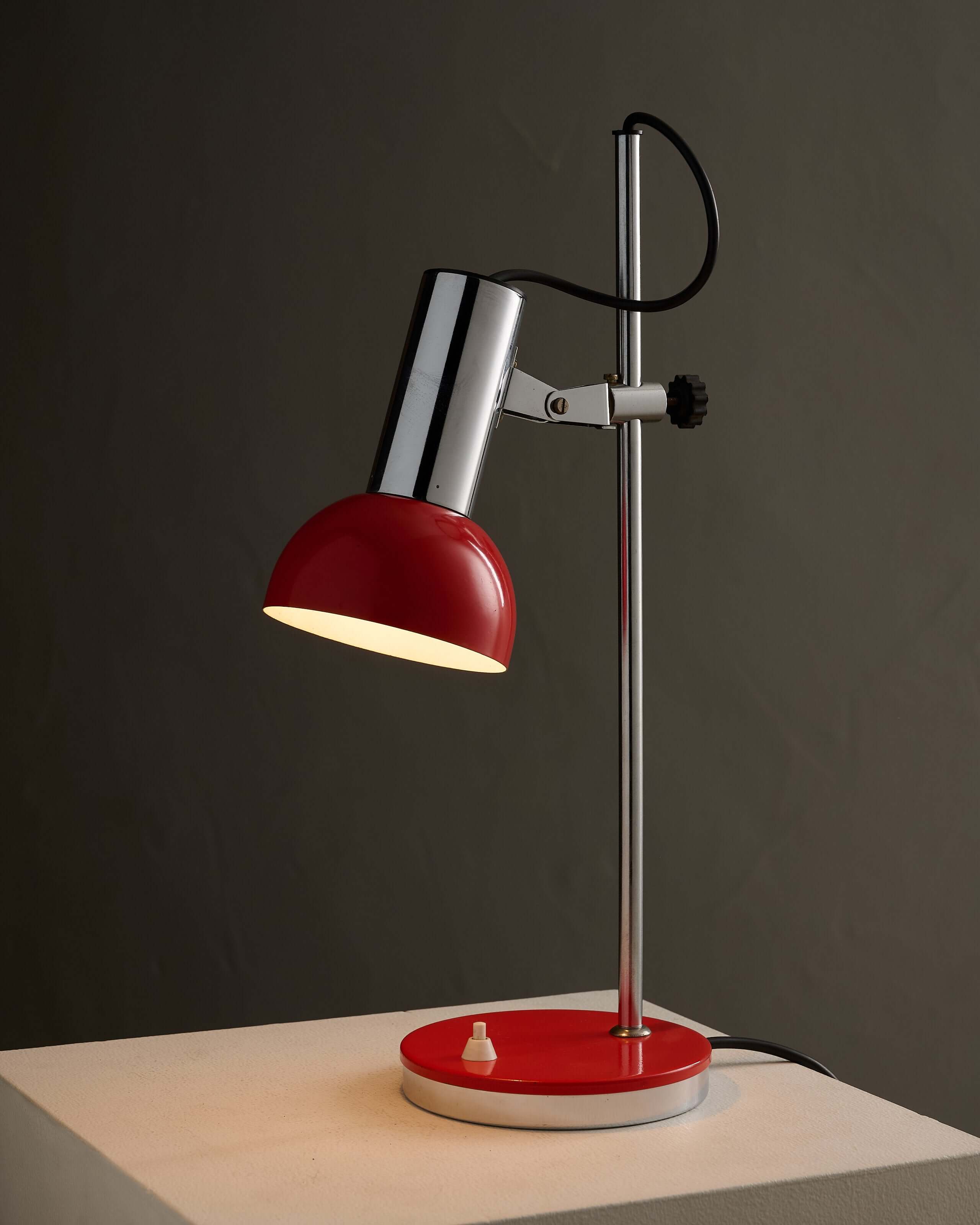 Adjustable chrome red table lamp with a red shade and chrome body, showcasing 1970s design.