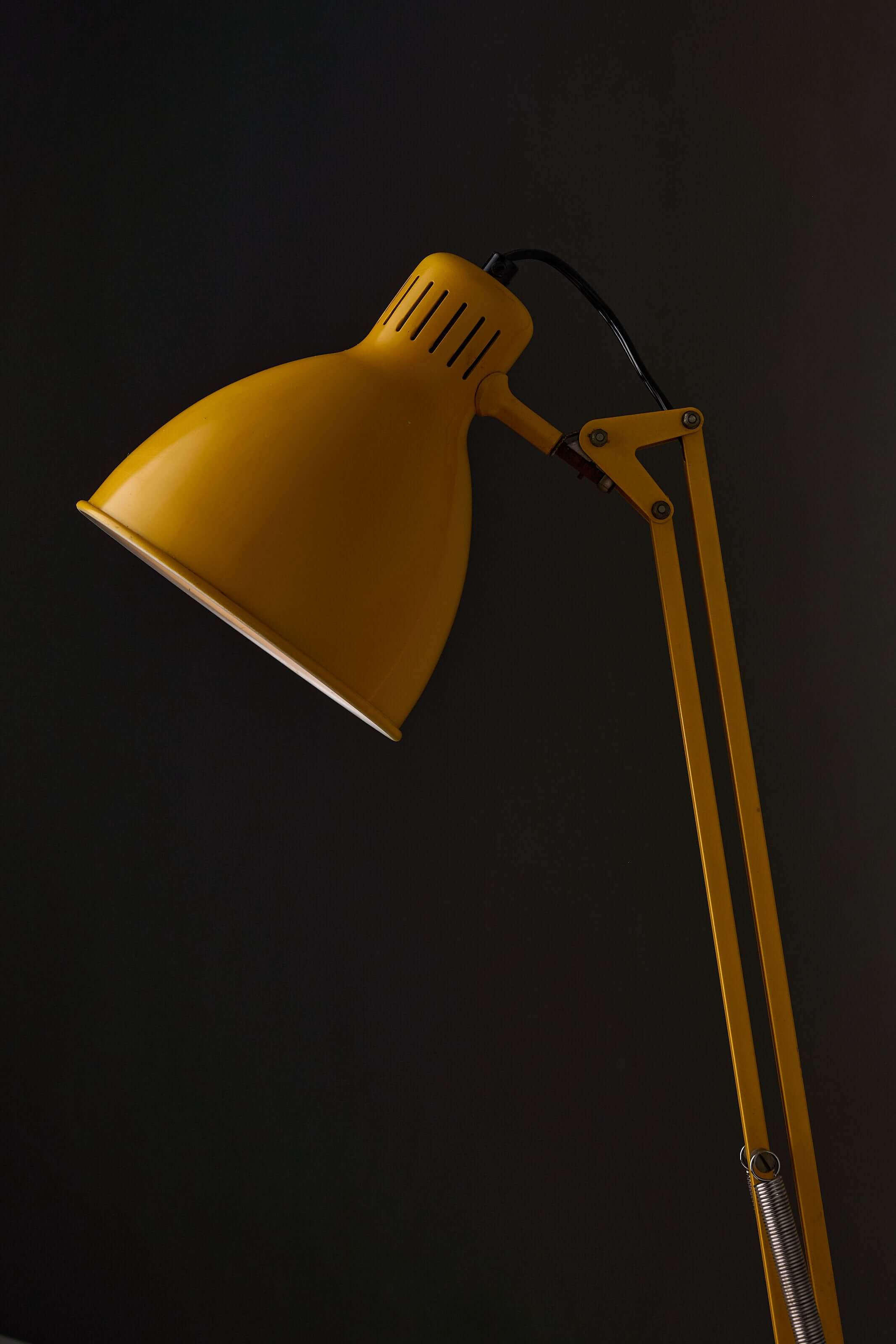 Yellow adjustable architect desk lamp with a balanced-arm mechanism and rotary switch.