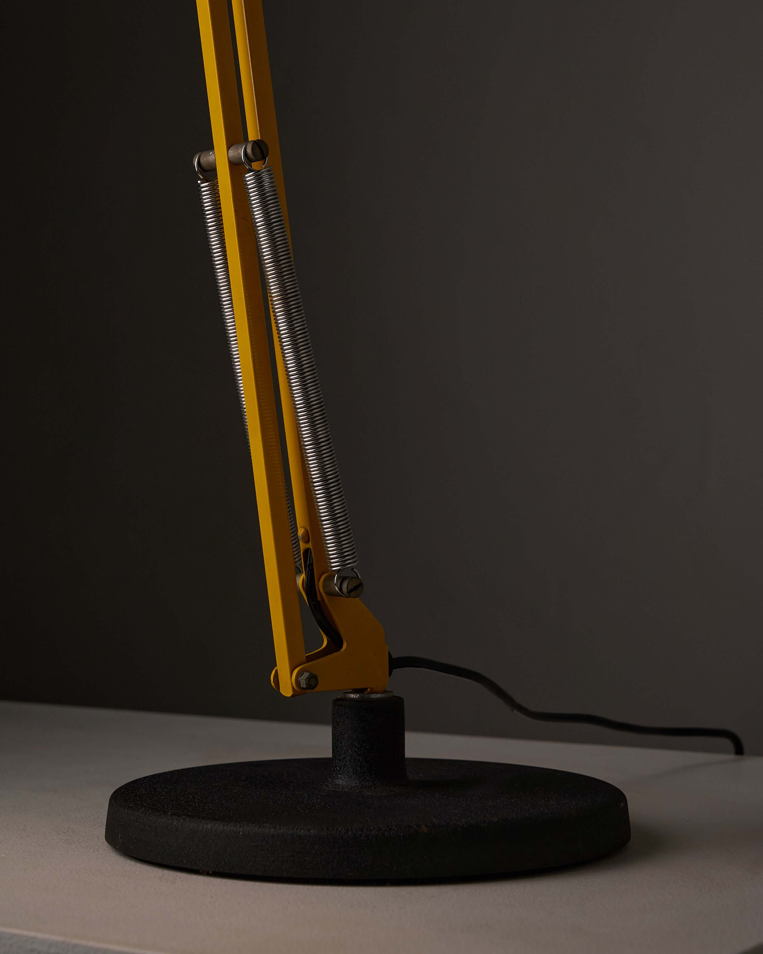 Yellow adjustable architect desk lamp featuring a classic balanced-arm mechanism and heavy cast iron base.