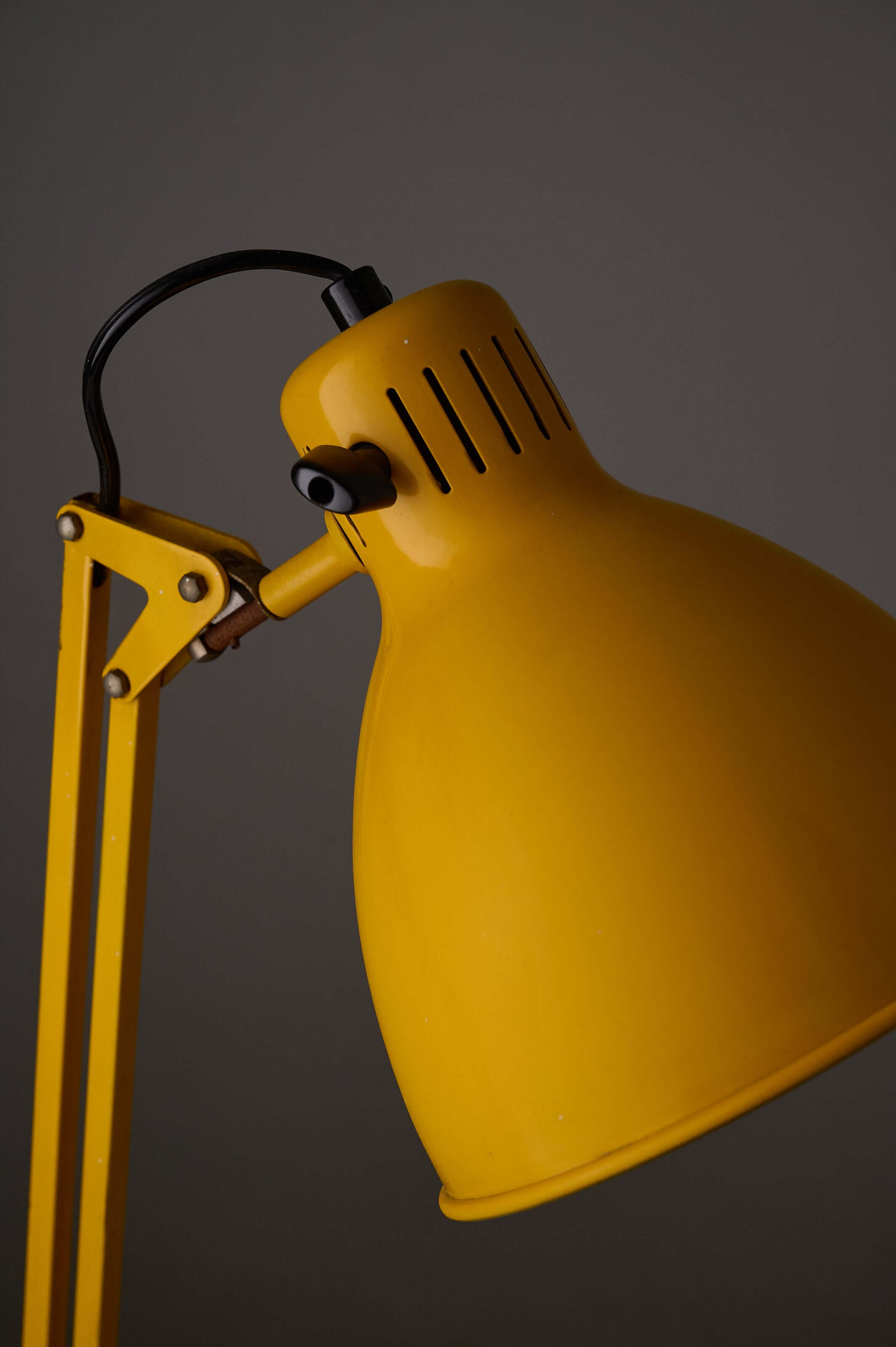 Yellow adjustable architect desk lamp with balanced-arm mechanism and rotary switch.