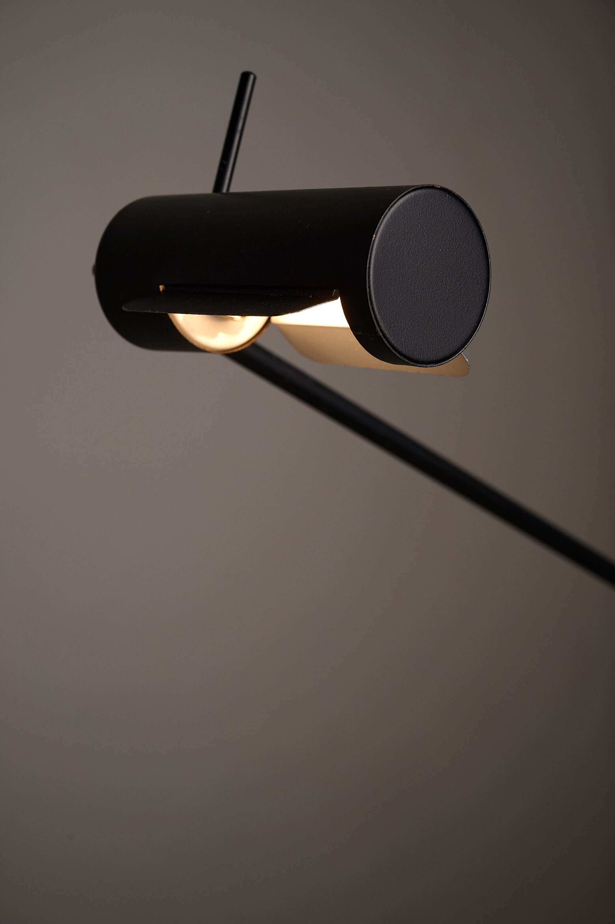 Matte black counterbalance desk lamp by Sische, featuring a cylindrical head and adjustable shield for glare control.