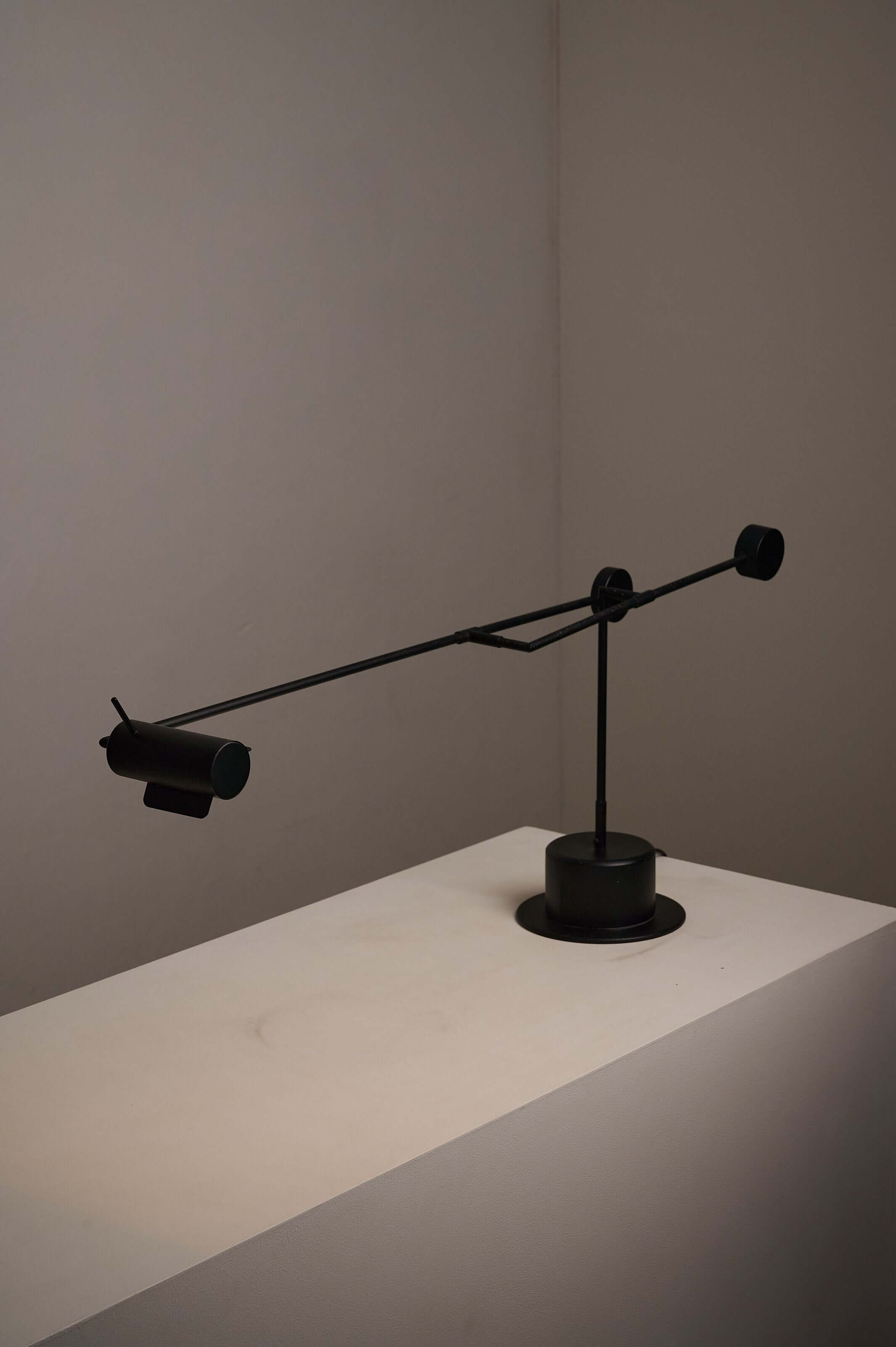 Matte black counterbalance desk lamp by Sische elegantly positioned on a minimalist white surface.
