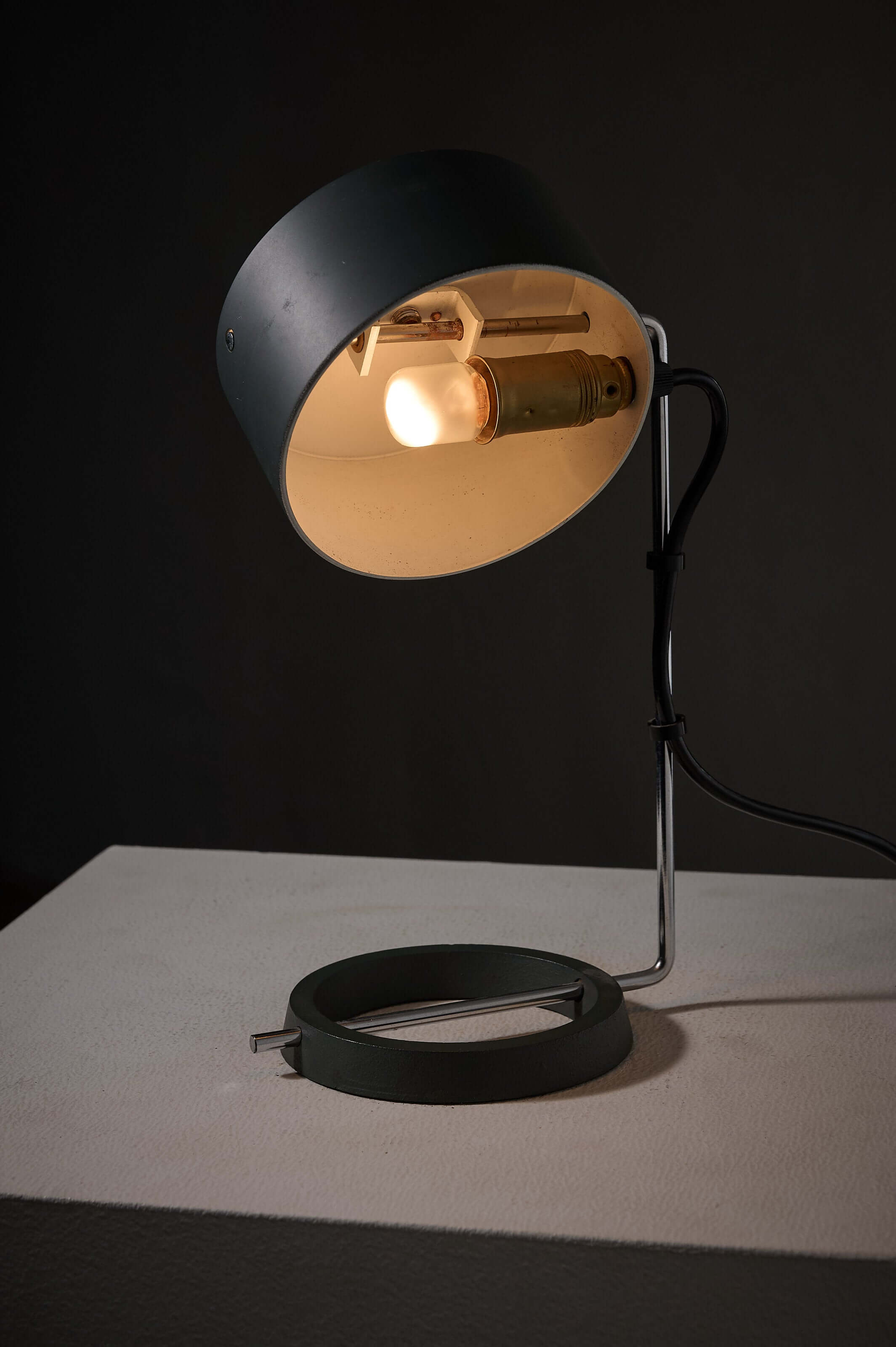 Adjustable minimalist desk lamp with industrial design and heavy ring base in anthracite and chrome finish.