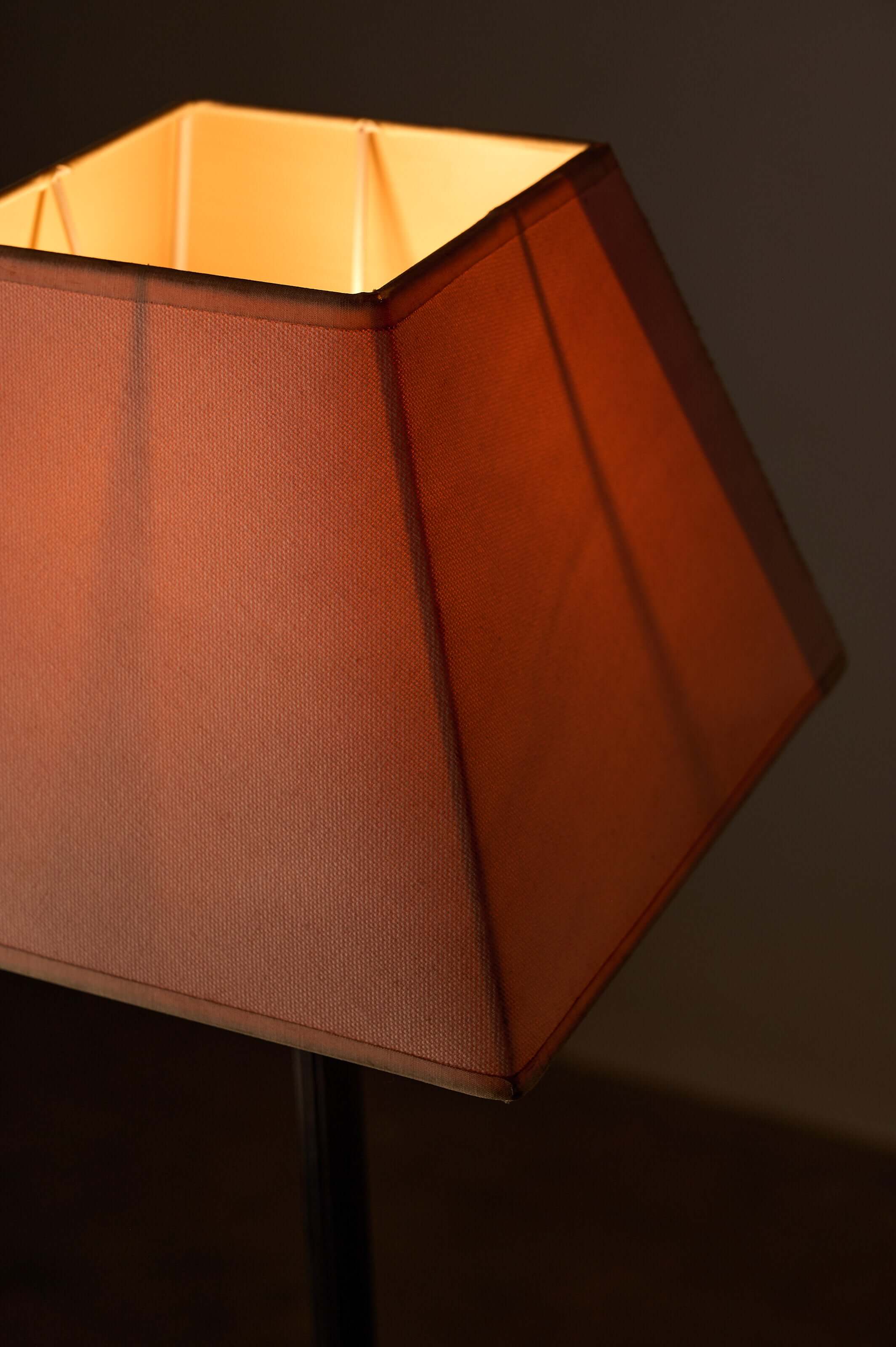 Close-up of a tapered square fabric shade of a neoclassical metal table lamp, showcasing warm light diffusion.