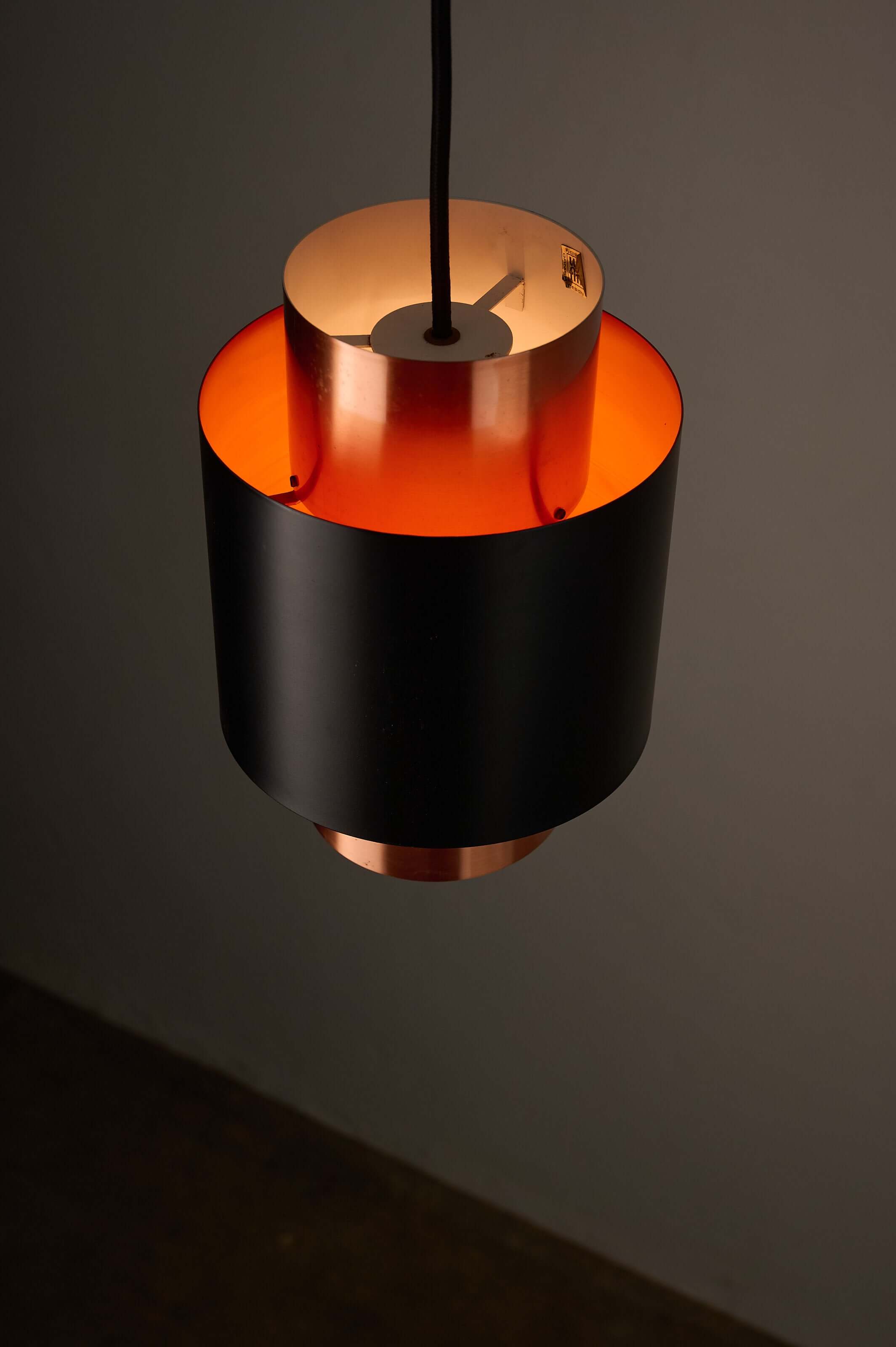 Black and Copper "Tunika" Pendant by Jo Hammerborg for Fog & Mørup, 1960 showcasing a layered design with warm orange lighting.