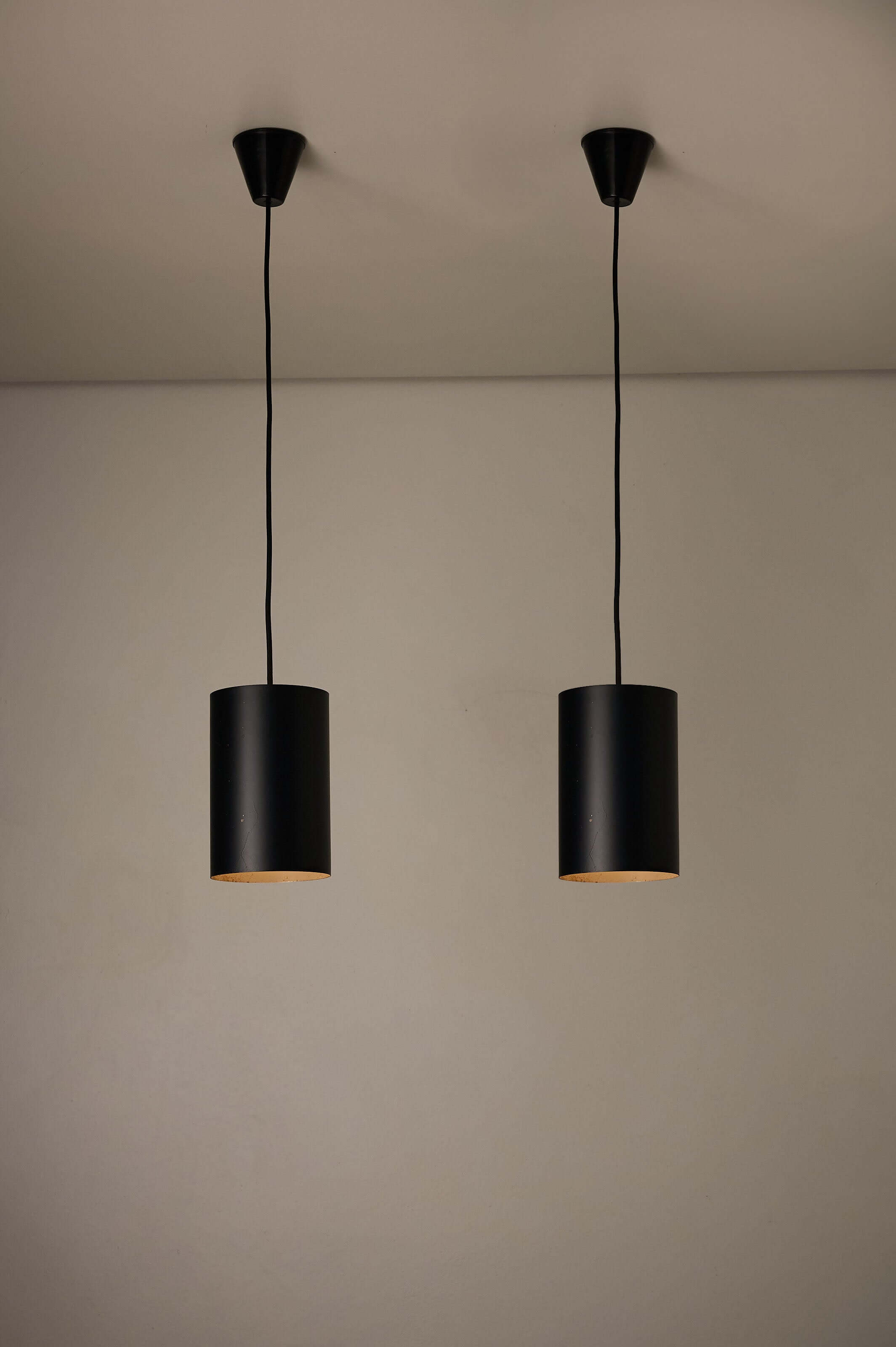 Minimalist Black Cylinder Pendant by Fog & Mørup, 1960s hanging from the ceiling, showcasing a matte black finish.