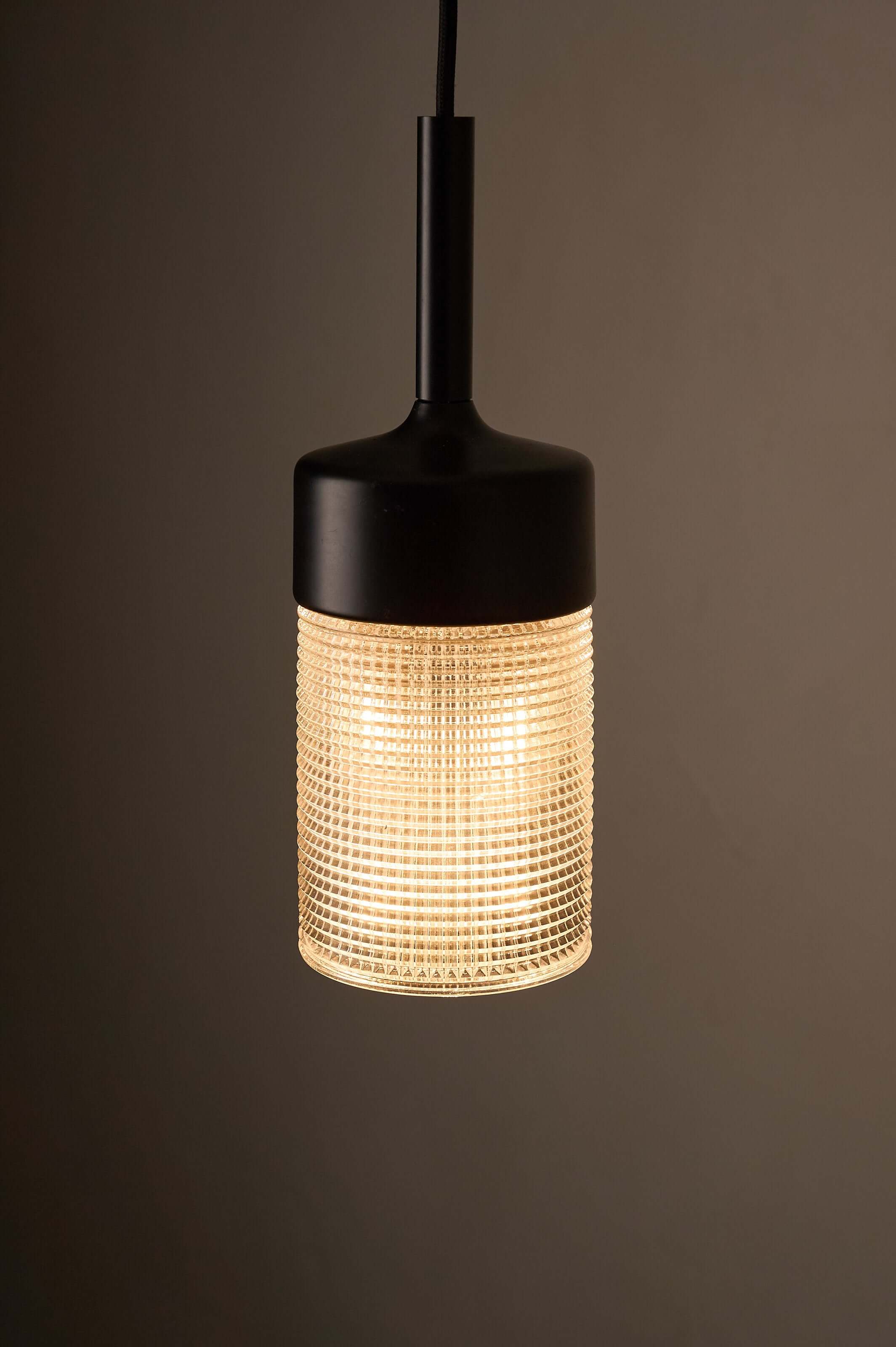 Black model structured glass pendant light featuring geometric grid pattern and warm glow.