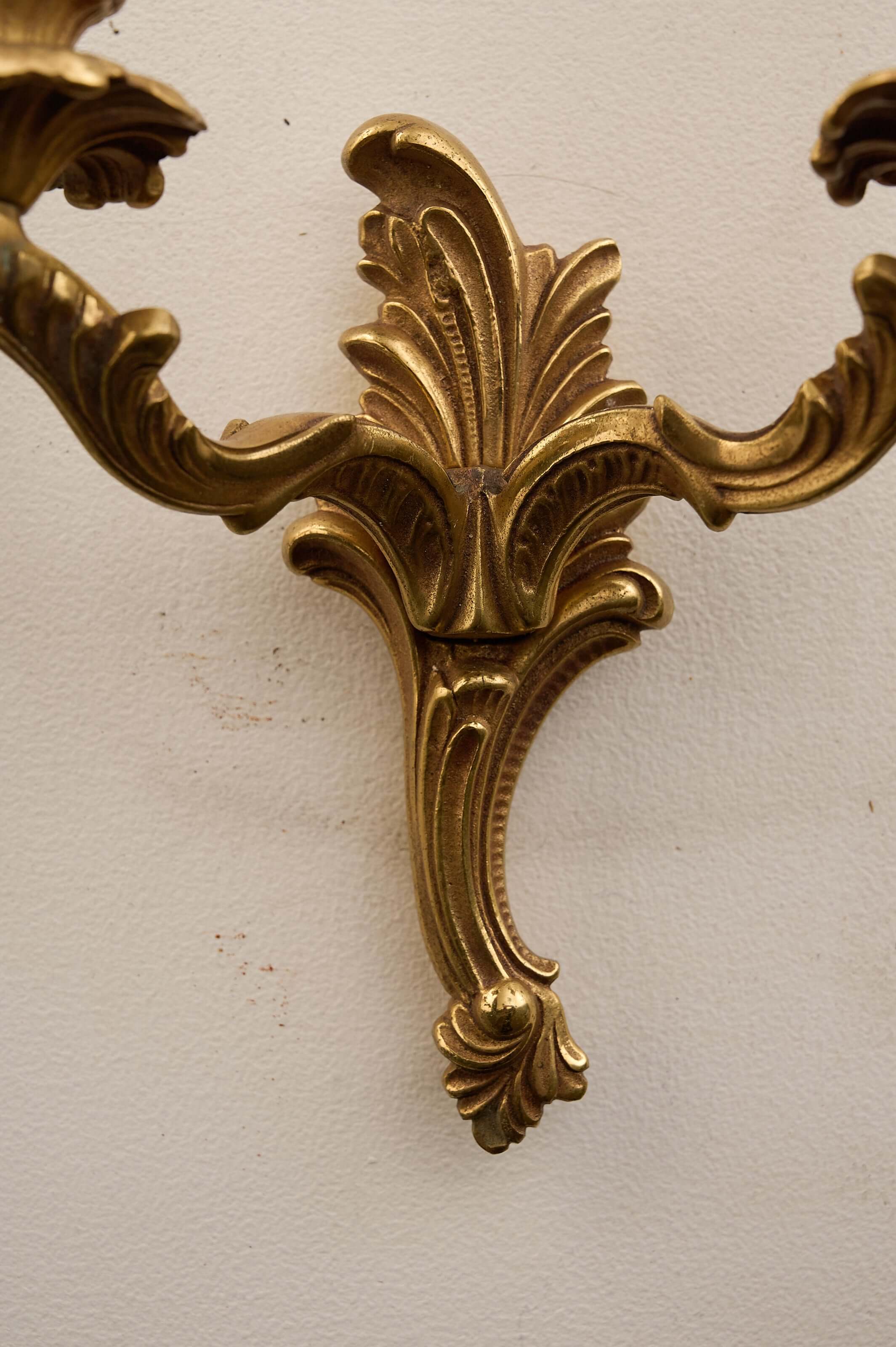 Close-up of Louis XV style brass wall sconces showing ornate detailing and stylized acanthus leaves.