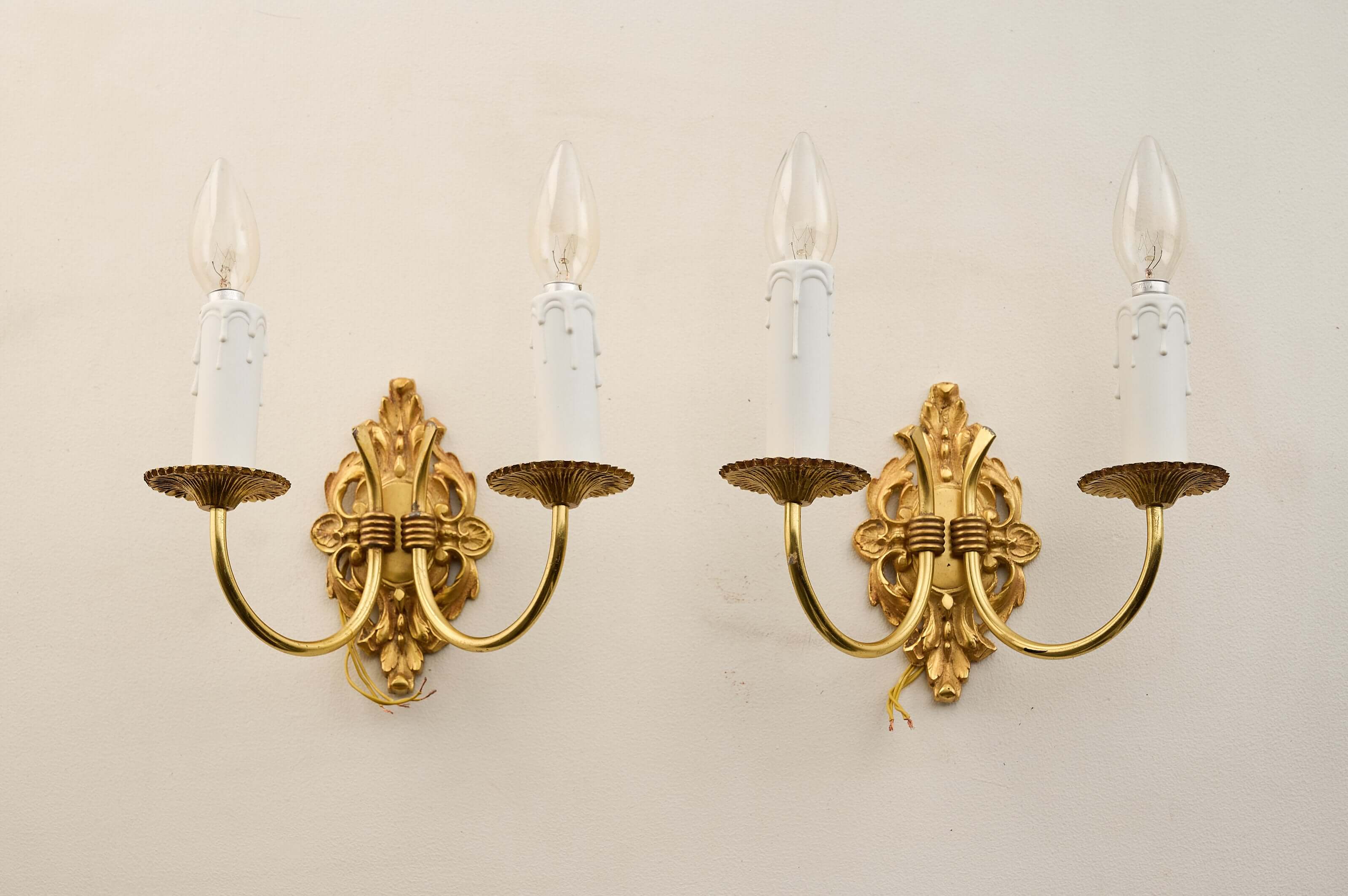 Pair of Empire style brass wall sconces with double arms and stylized foliage design.