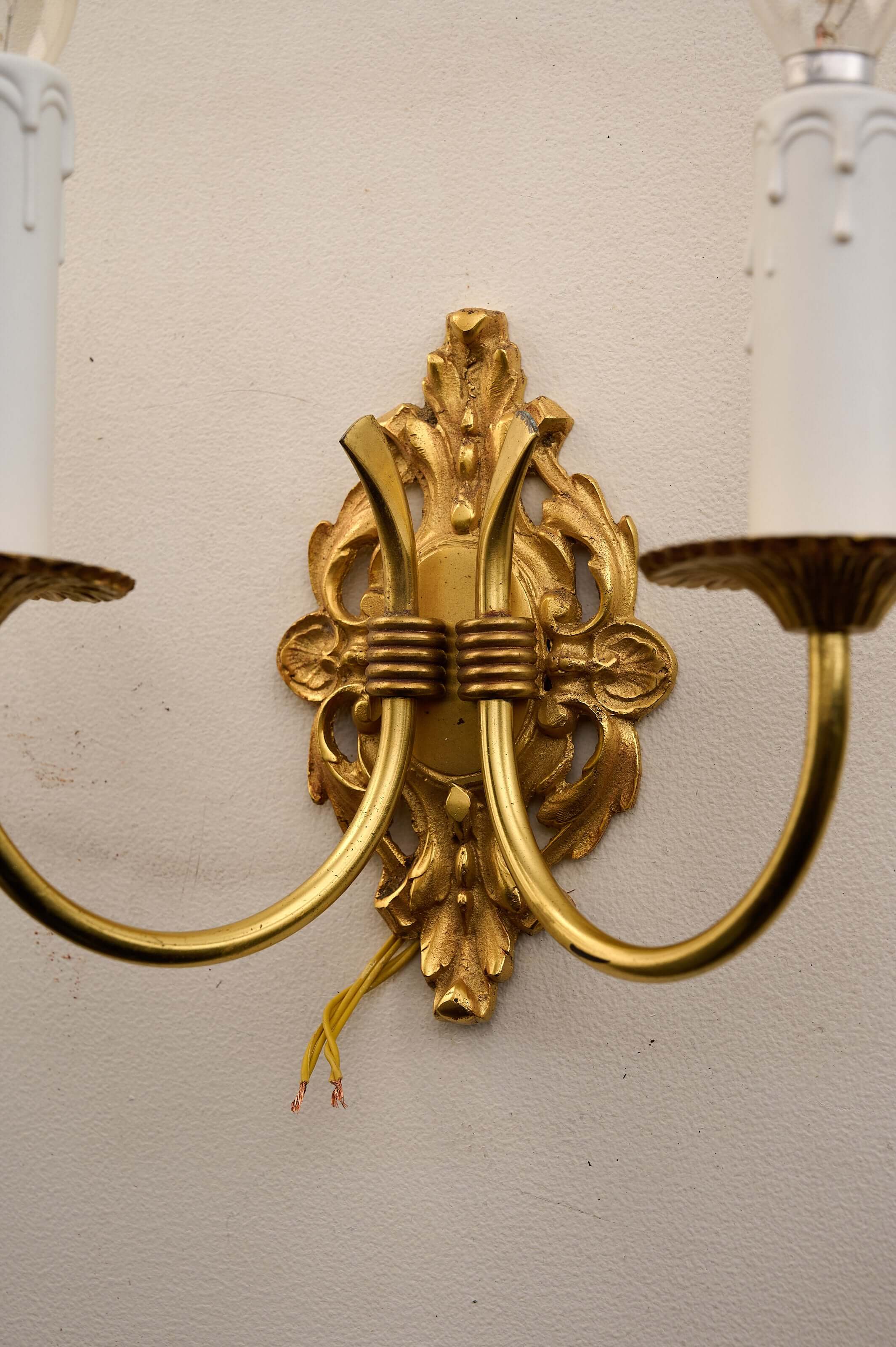 Empire style brass wall sconces featuring detailed foliage relief and double-arm design.