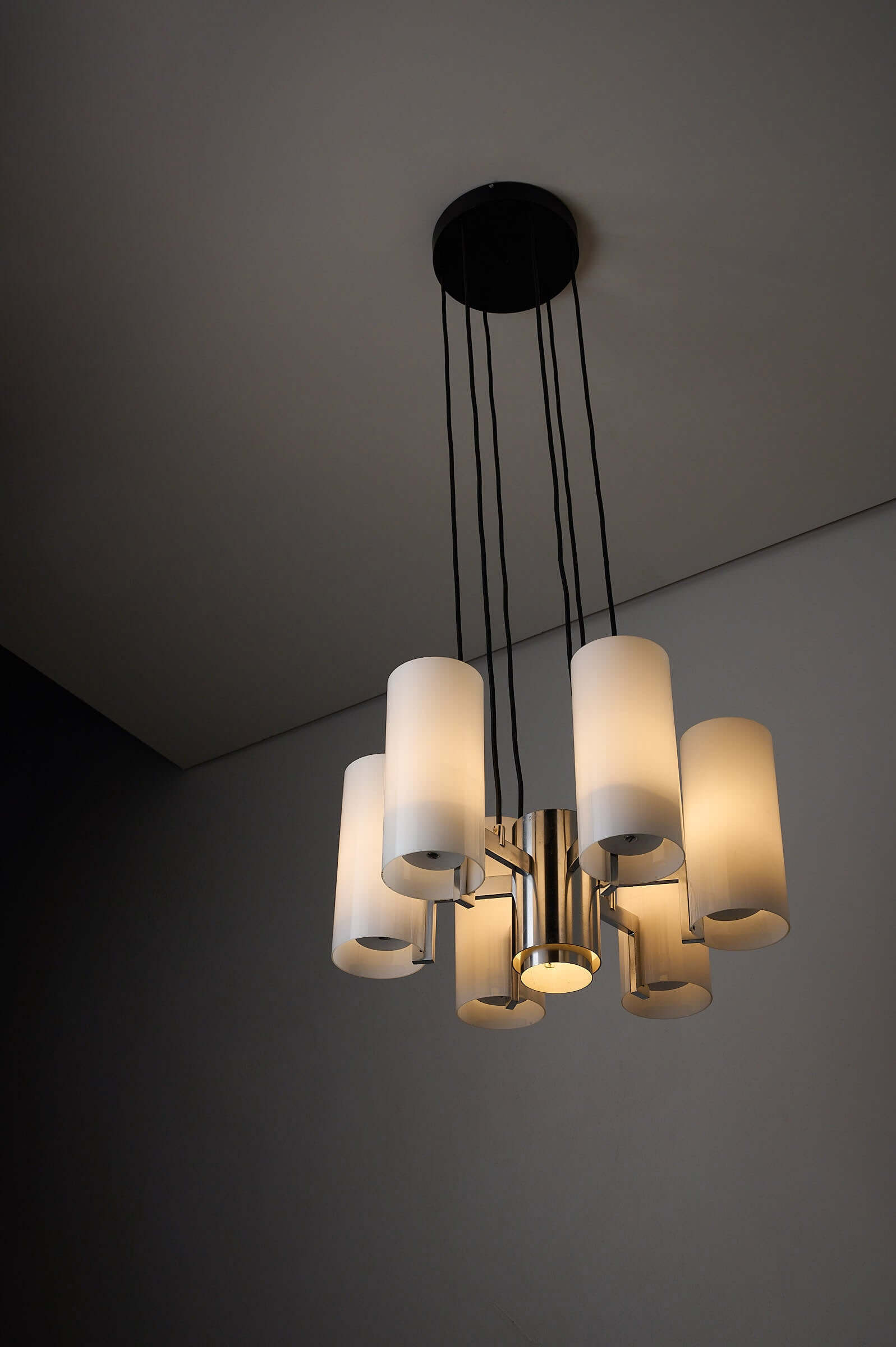 Space Age Chrome and Opaline Glass Chandelier with Six Cylindrical Shades hanging from the ceiling.