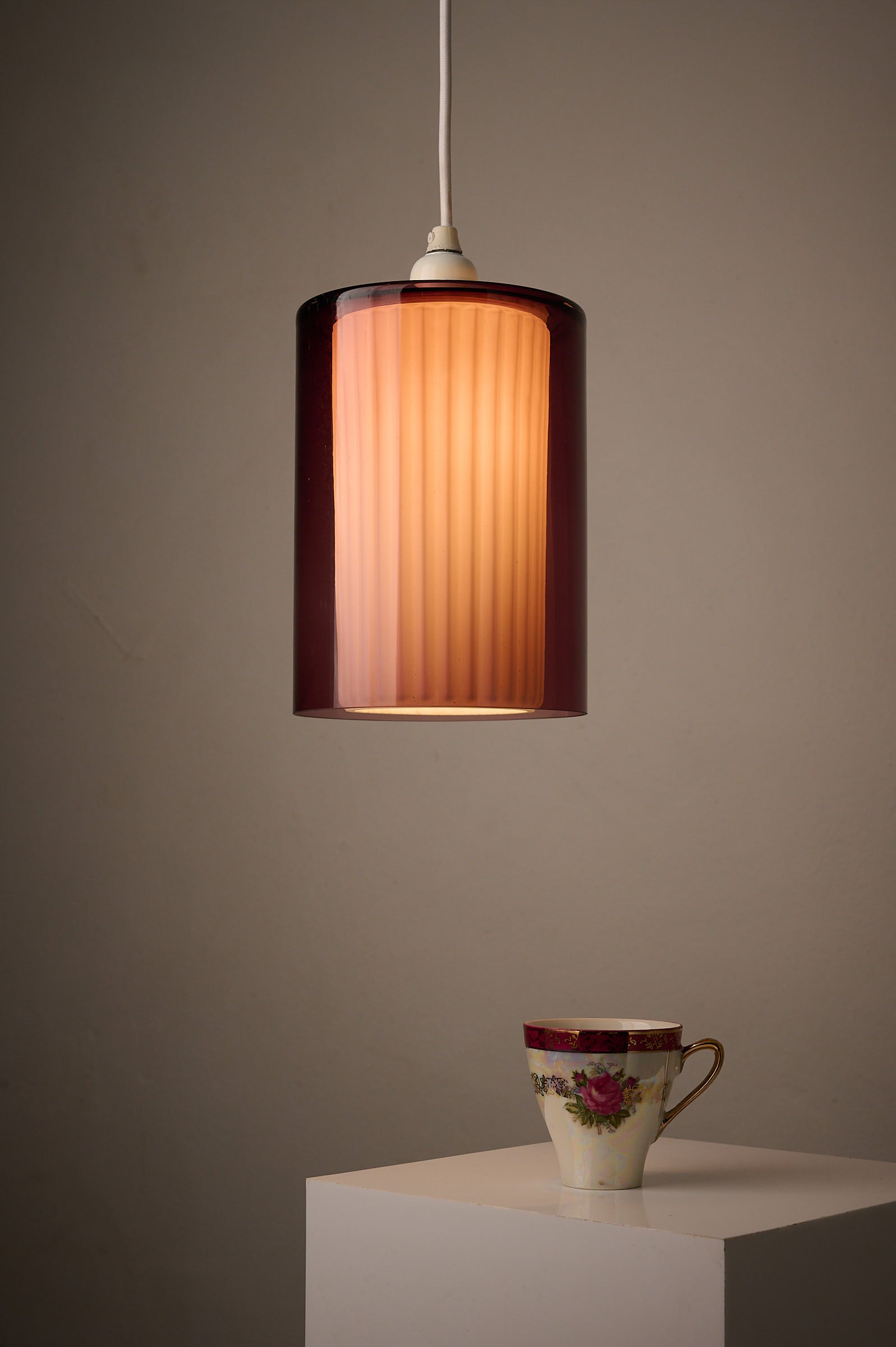 Double Glass Pendant in Lilac and Opaline, Europe, 1960s/1970s hanging above a floral teacup.